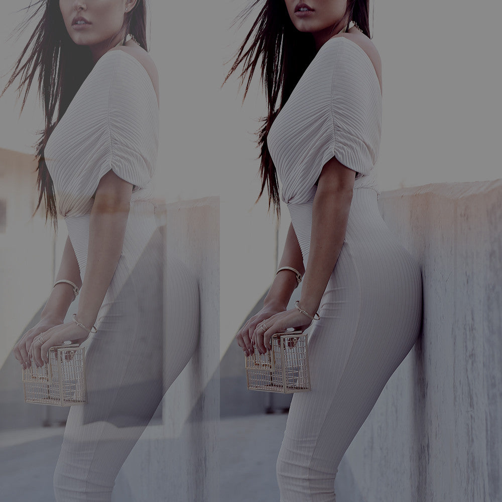 Woman in a white ribbed dress with puff sleeves leaning against a rooftop wall; mirrored crop.