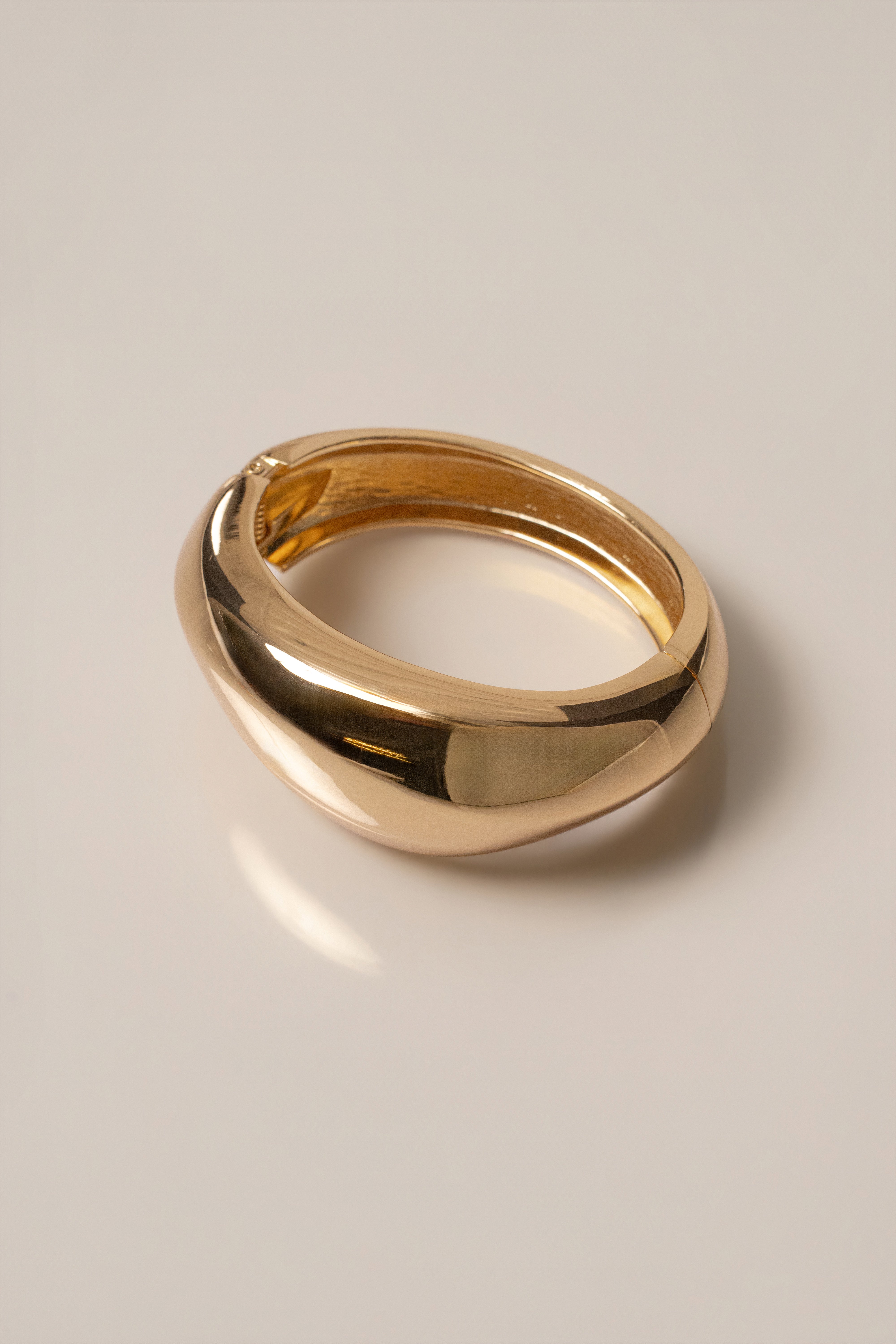 Close up of a glossy yellow gold Vittoria hinge bracelet with rounded edges