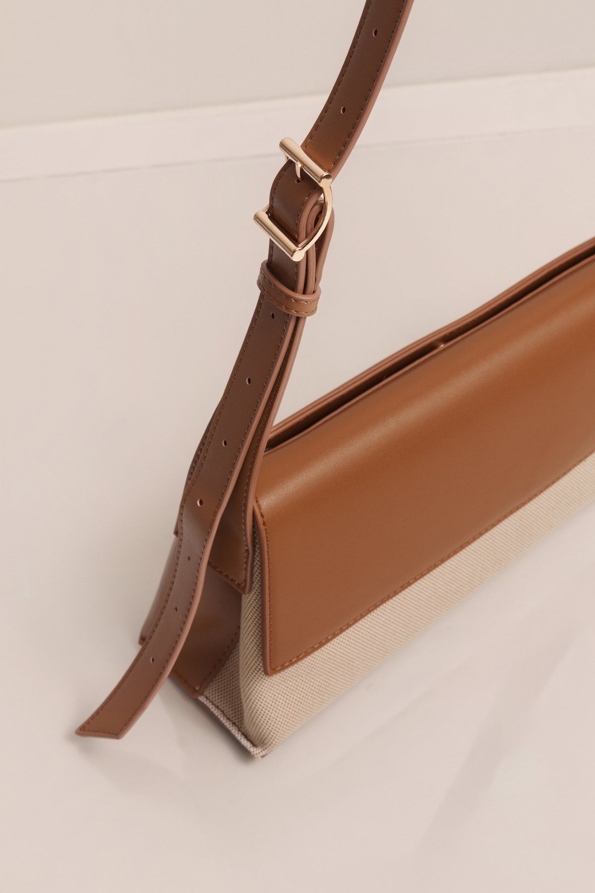 Beige JLUXLABEL Hudson shoulder bag with adjustable strap and gold-tone hardware, styled as a versatile accessory.