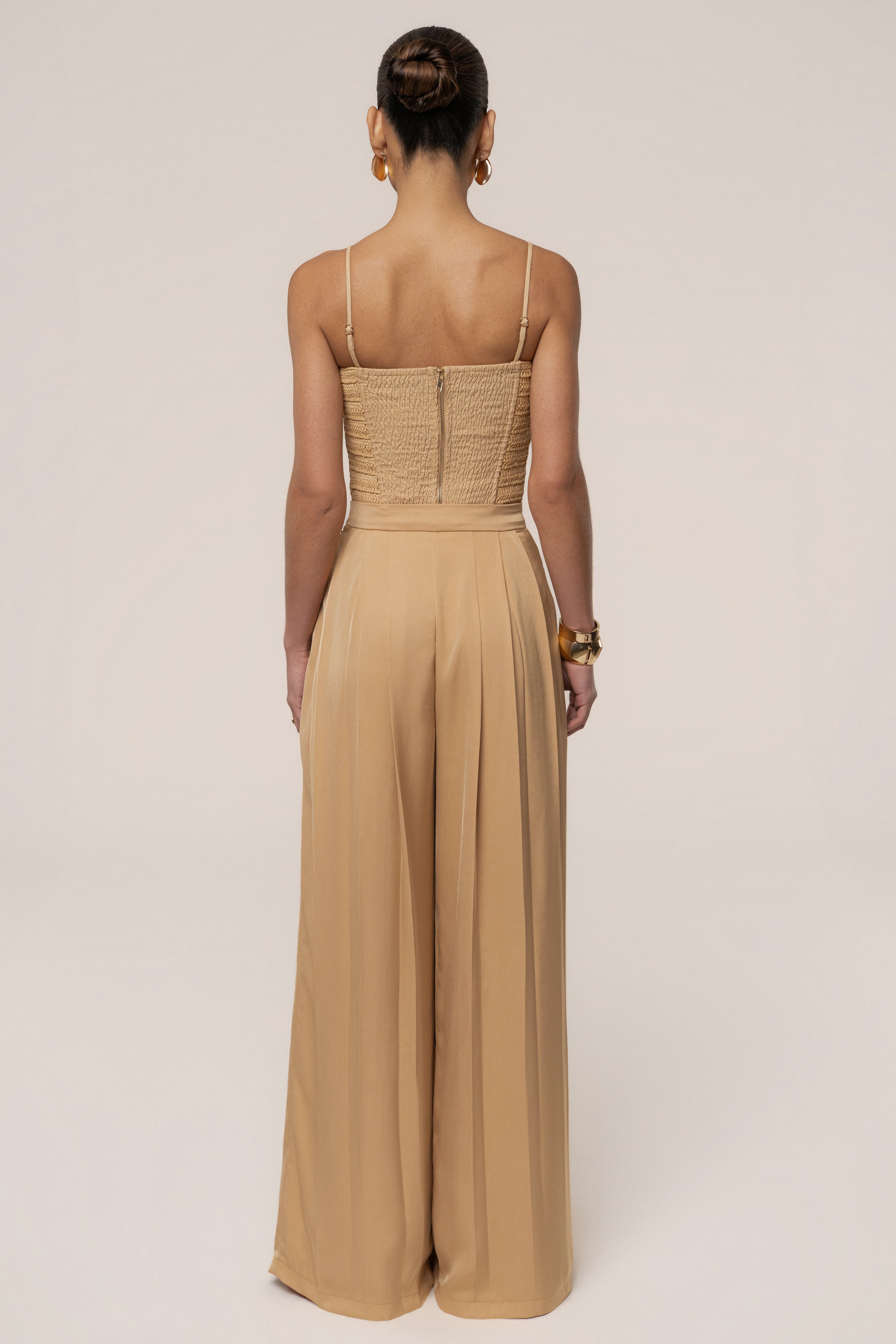 Beige Clara wide-leg pleated trousers from JLUXLABEL, featuring flowing fabric and high waist, styled with a matching top.