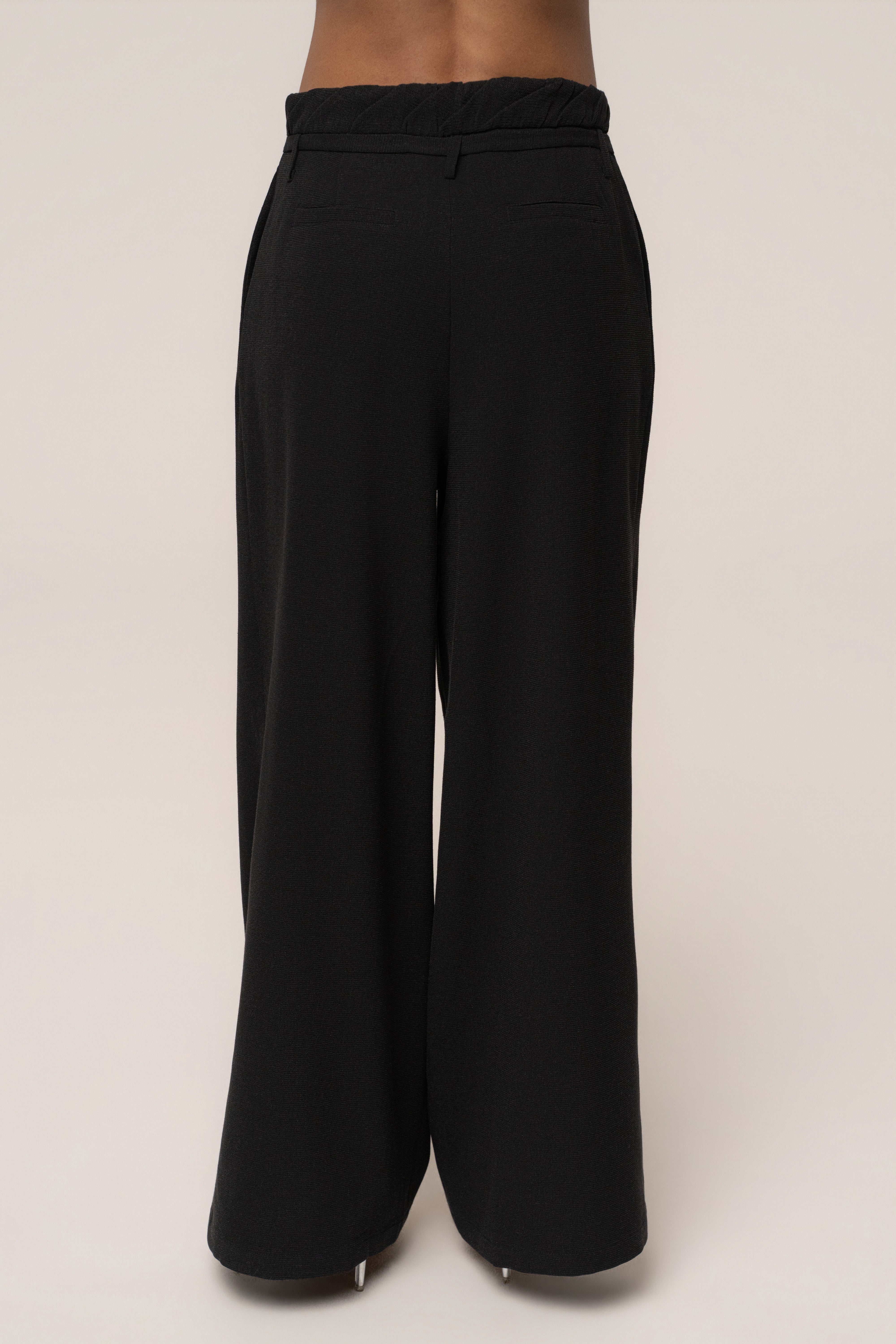 Black JLUXLABEL Refined Ease wide-leg pants, stylish bottoms with a relaxed fit, shown on a model in a casual setting.