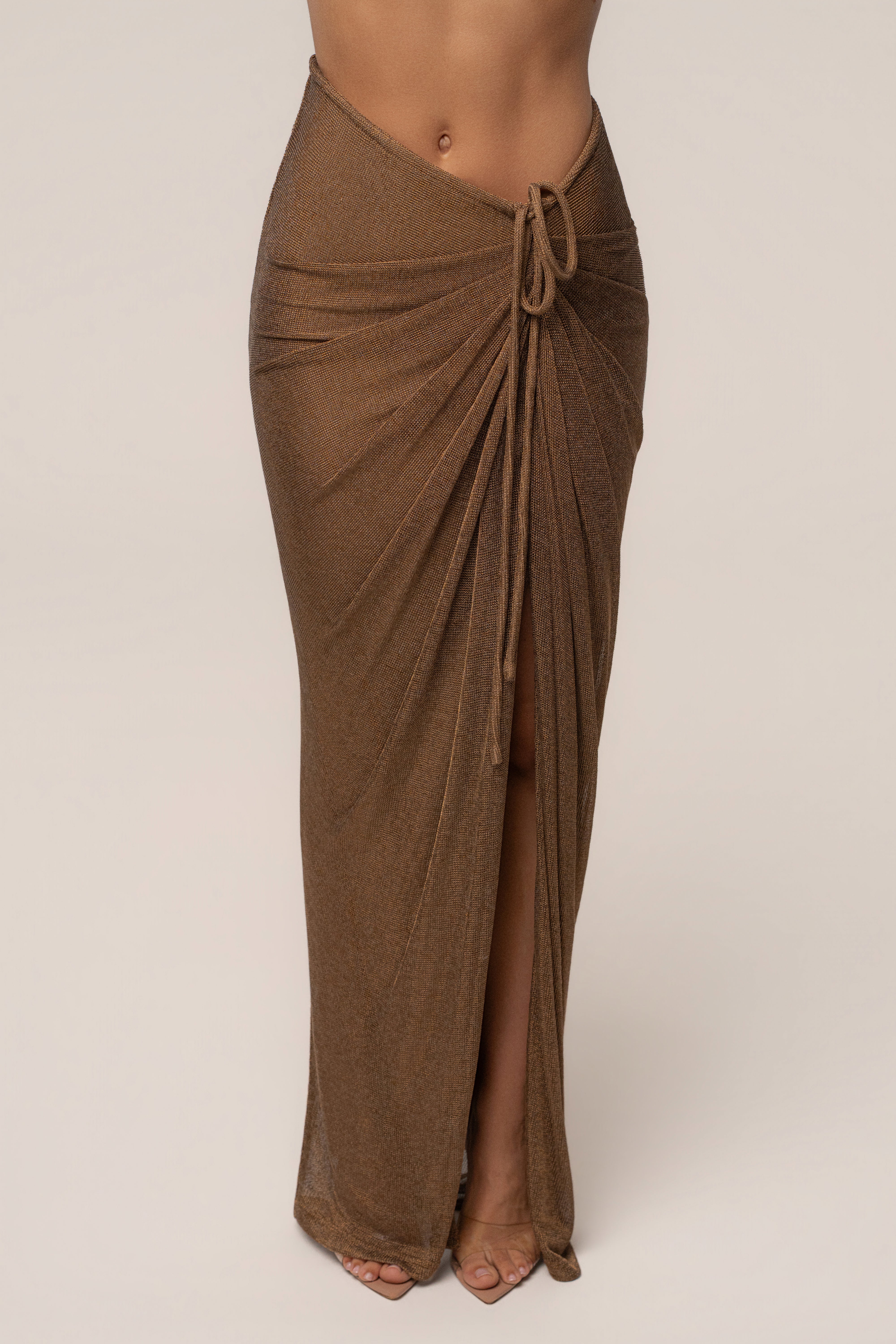 Bronze Noelia metallic slit skirt by JLUXLABEL, shown in a stylish view highlighting the shiny metallic fabric and slit detail.