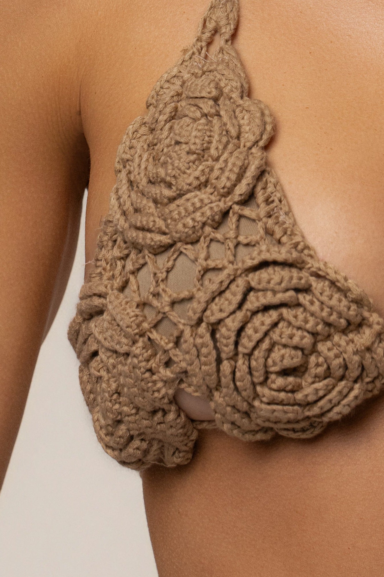 Close up of a tan khaki Beachside crochet bikini top on the shoulder highlighting chunky crochet stitches.