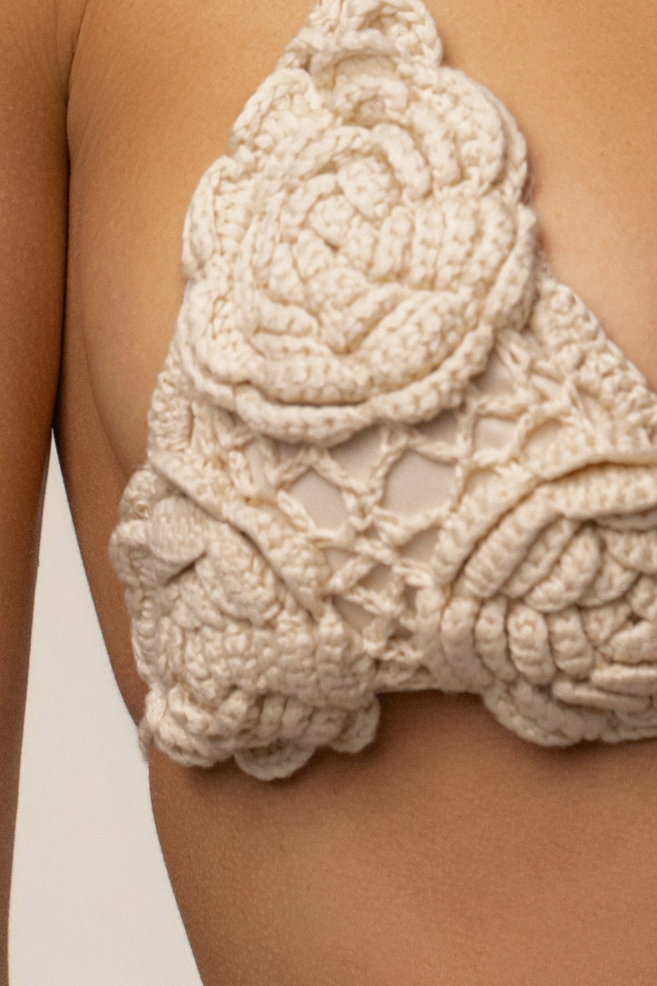 Beige crochet bikini top with chunky textured stitches and layered detail.