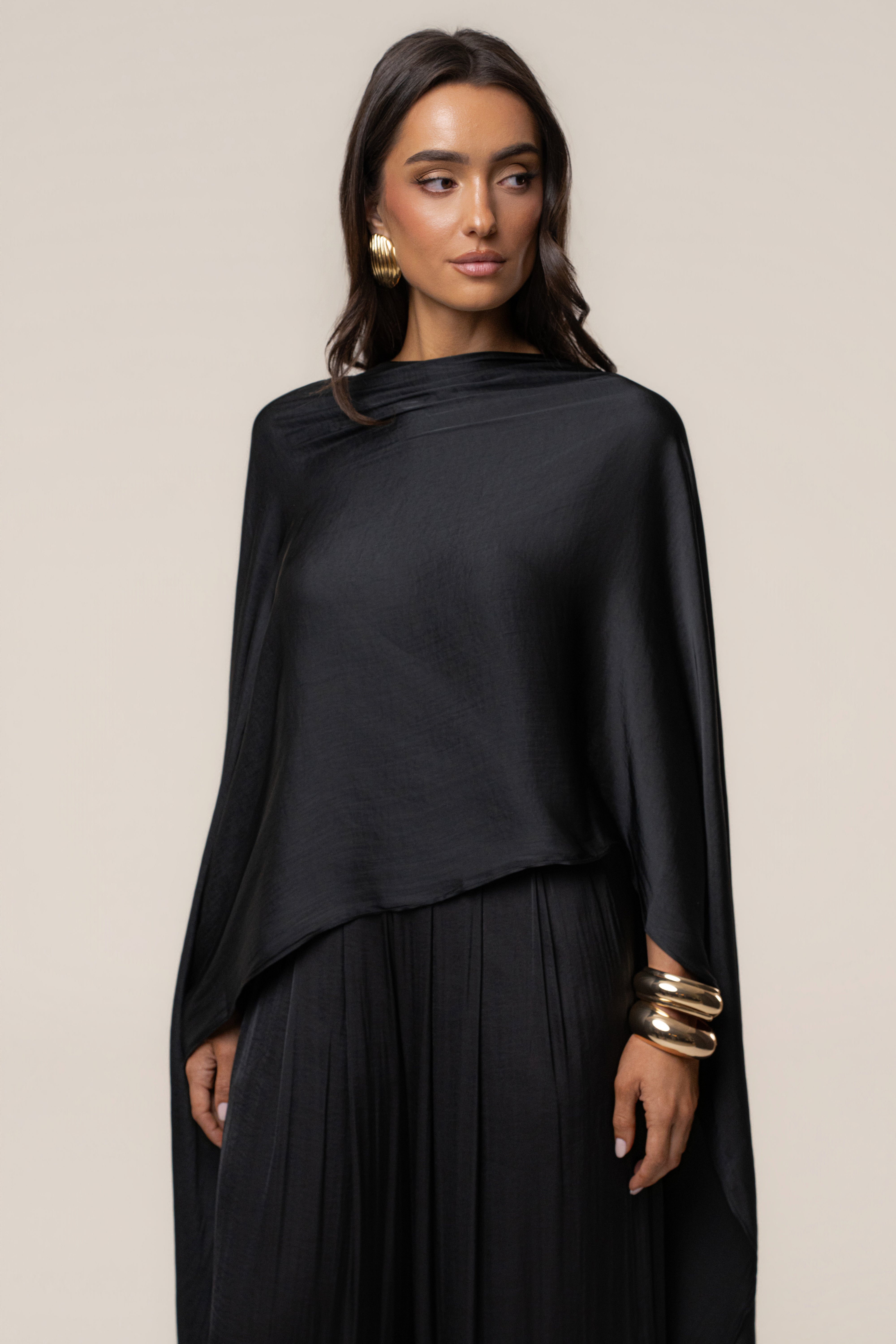 Full length portrait of model in Black Marina Multi-Wrap Scarf wrapped asymmetrically as a one-shoulder top.