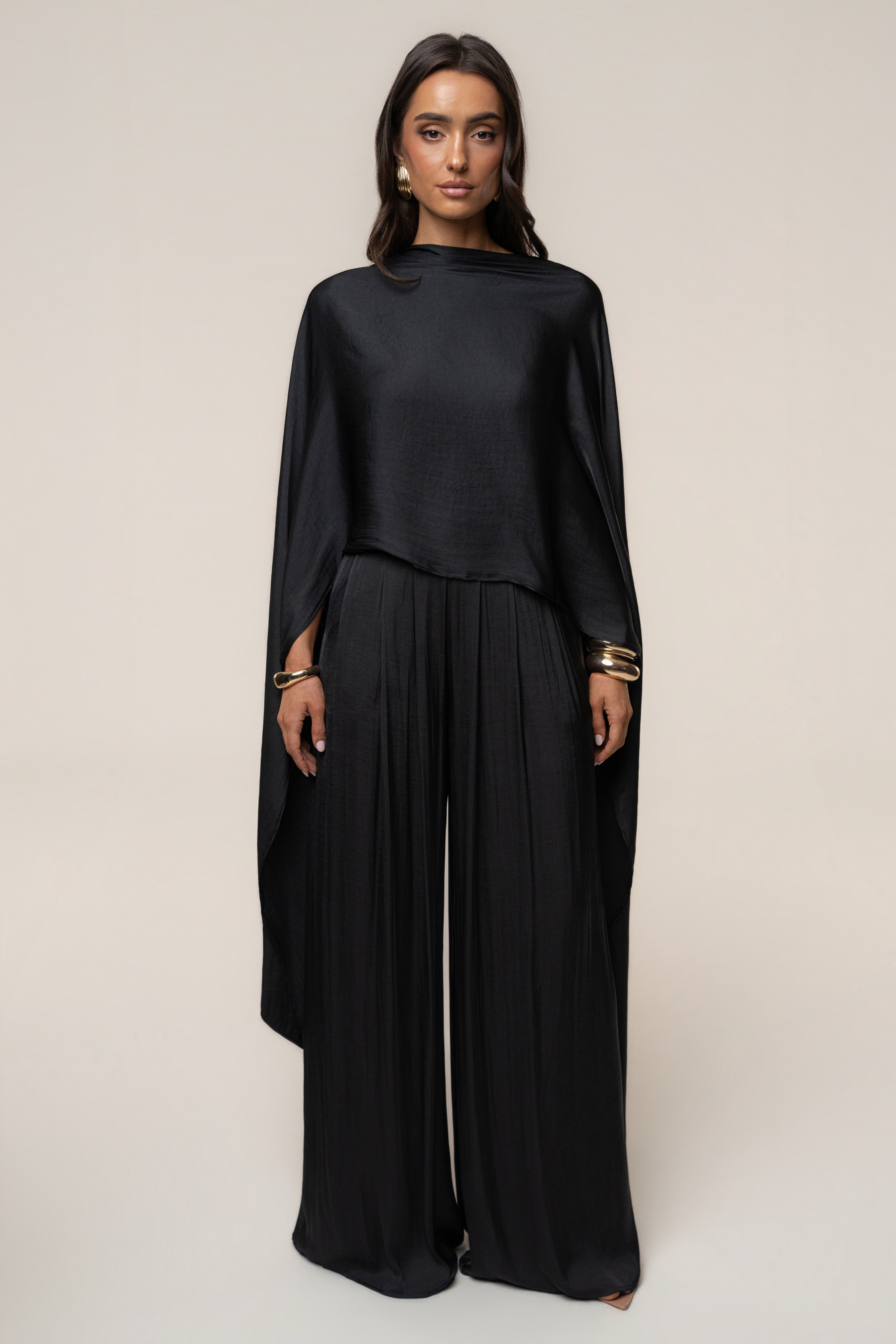 Model wearing Black Marina Multi-Wrap Scarf draped over shoulders with a flowing black outfit.