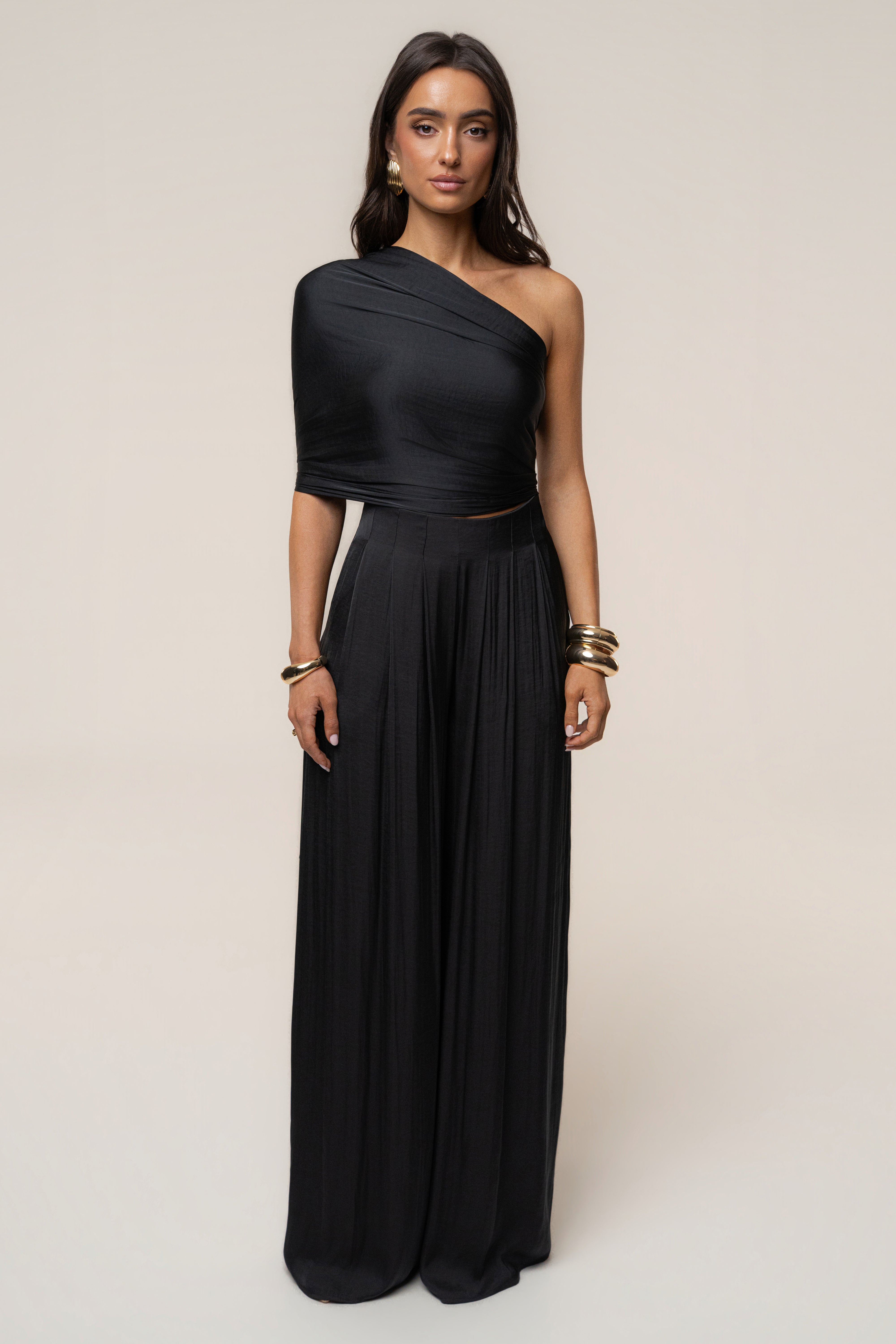 Model wearing the Black Marina Multi-Wrap Scarf styled as a single shoulder wrap with a black ensemble.