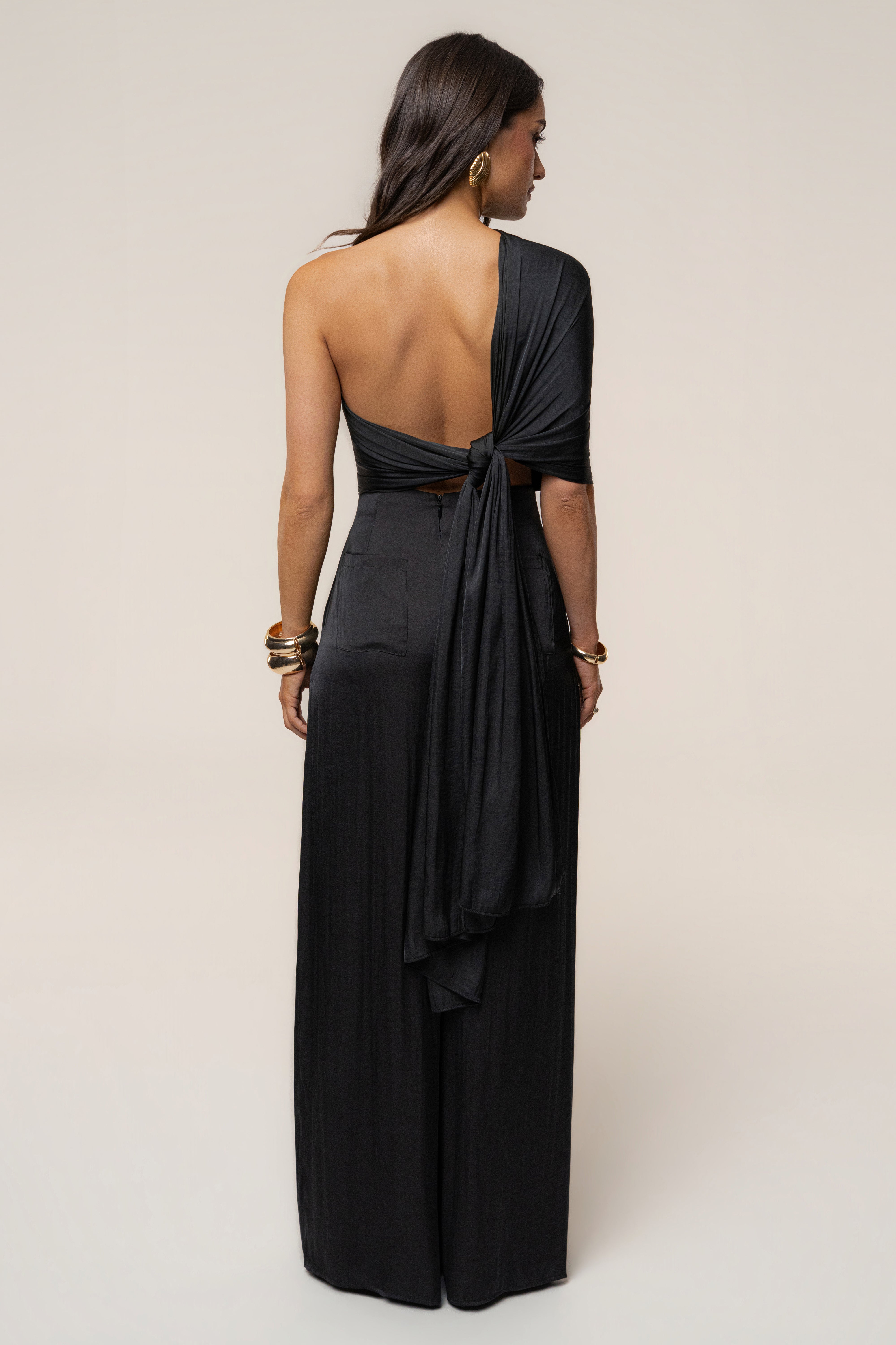 Back view of a model wearing the Black Marina Multi-Wrap Scarf tied at the lower back with long tails