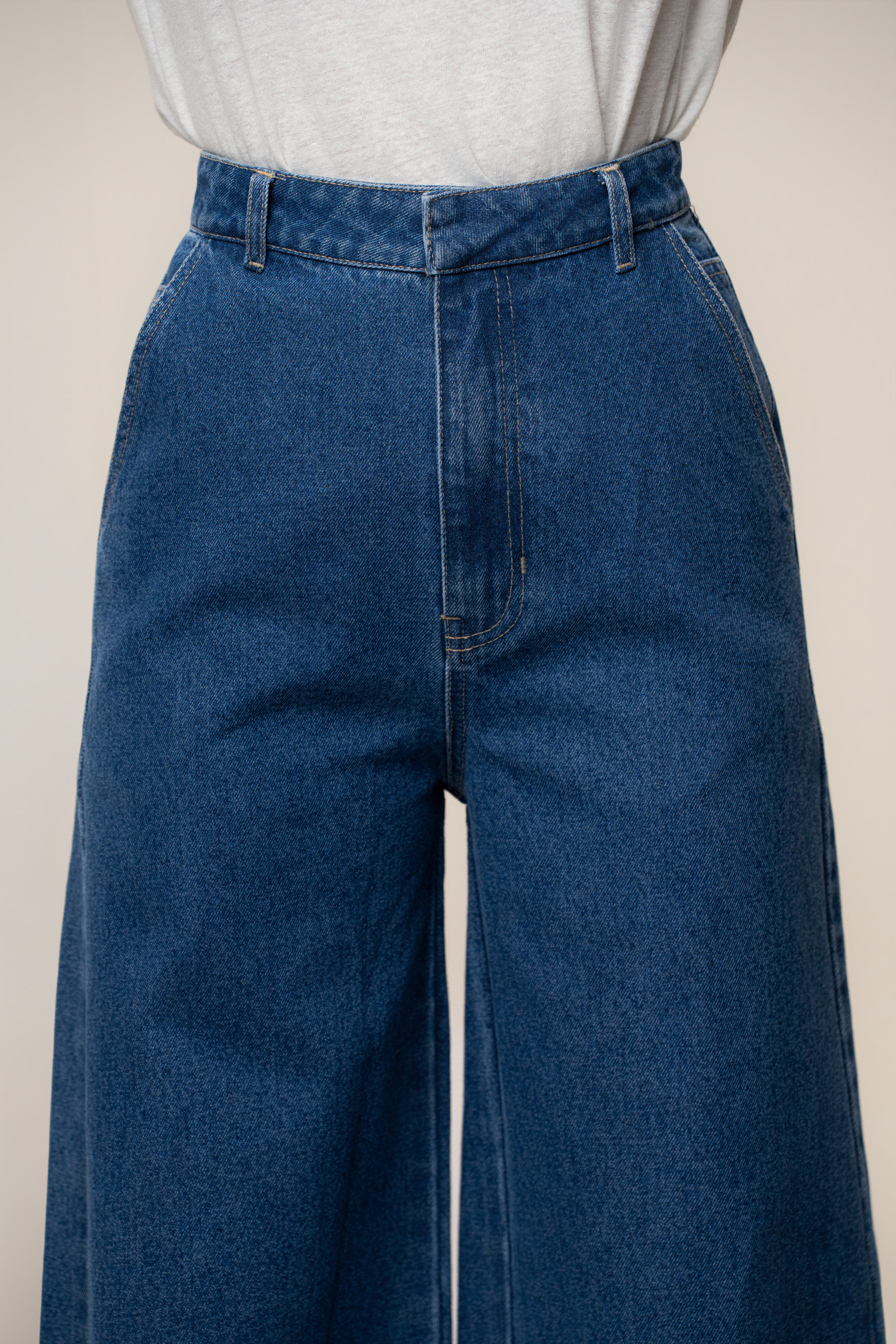 Close-up of the waist area showing belt loops and center seam on medium wash wide-leg jeans
