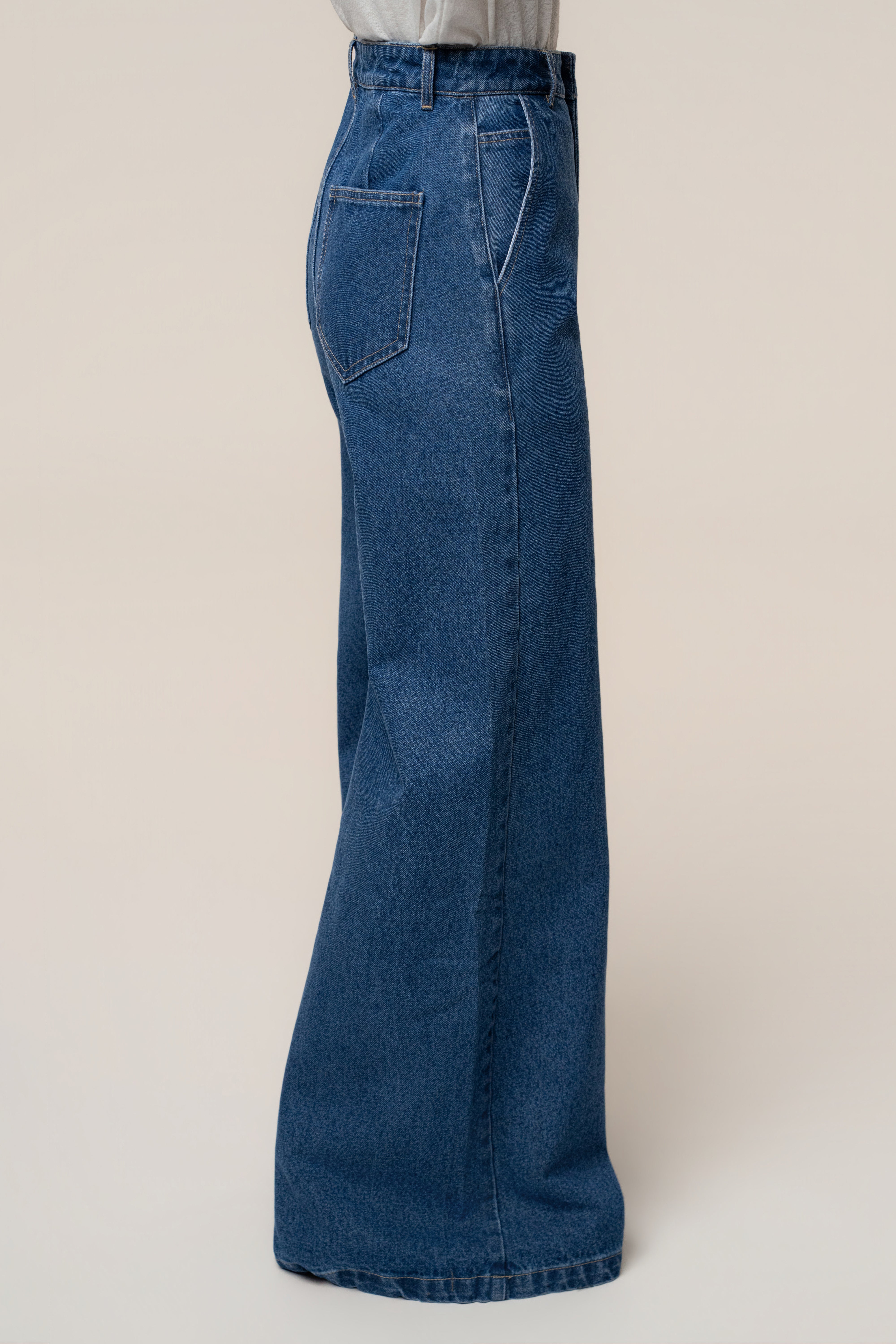 Full-length side view of medium wash wide leg denim jeans showing back pocket and wide leg opening.
