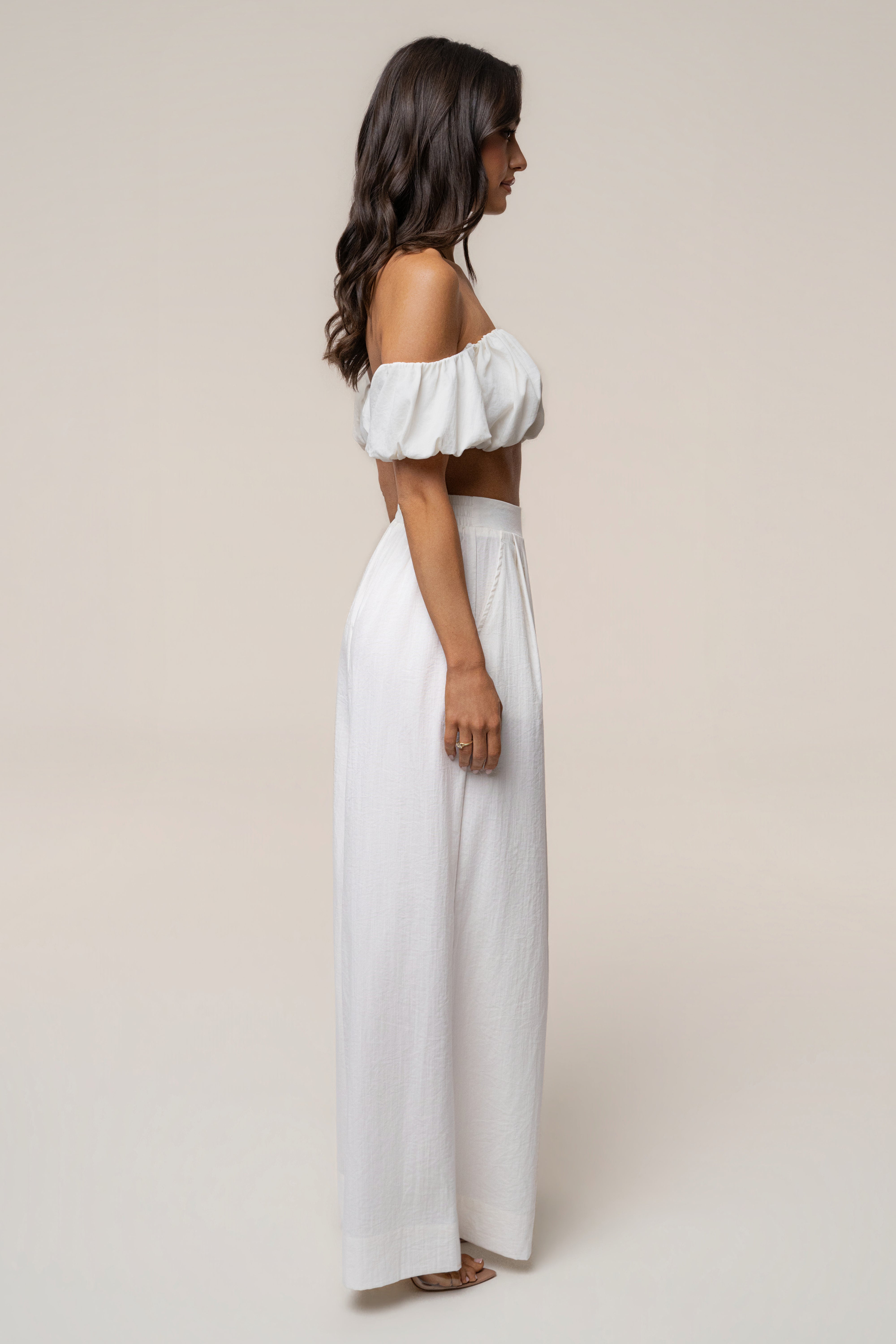 Profile view of the ivory Sunset Breeze pant set featuring off-shoulder top and long wide-leg pants with sandals.