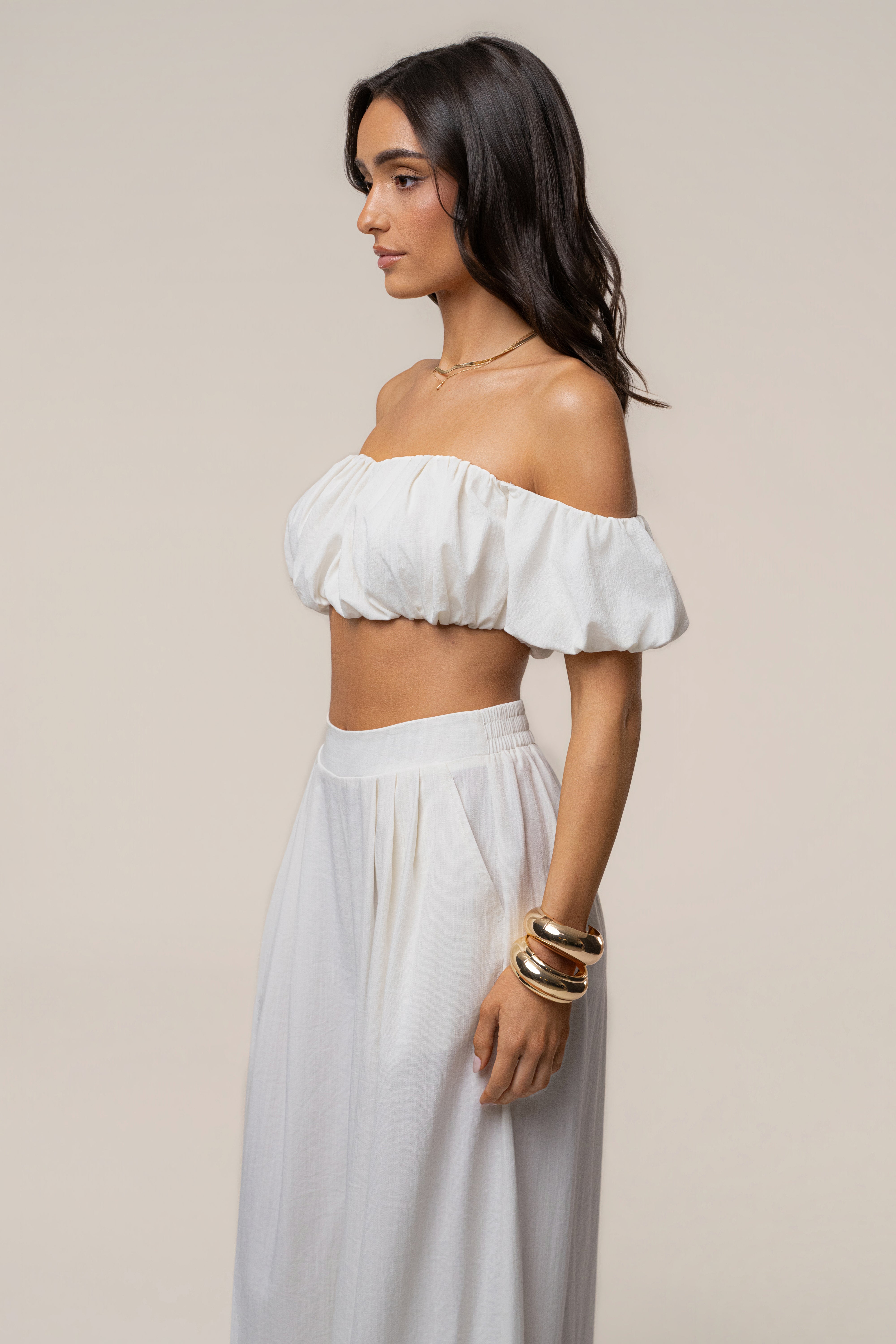 Side profile of model wearing ivory Sunset Breeze Pant Set featuring off-shoulder crop top and flowing pants.