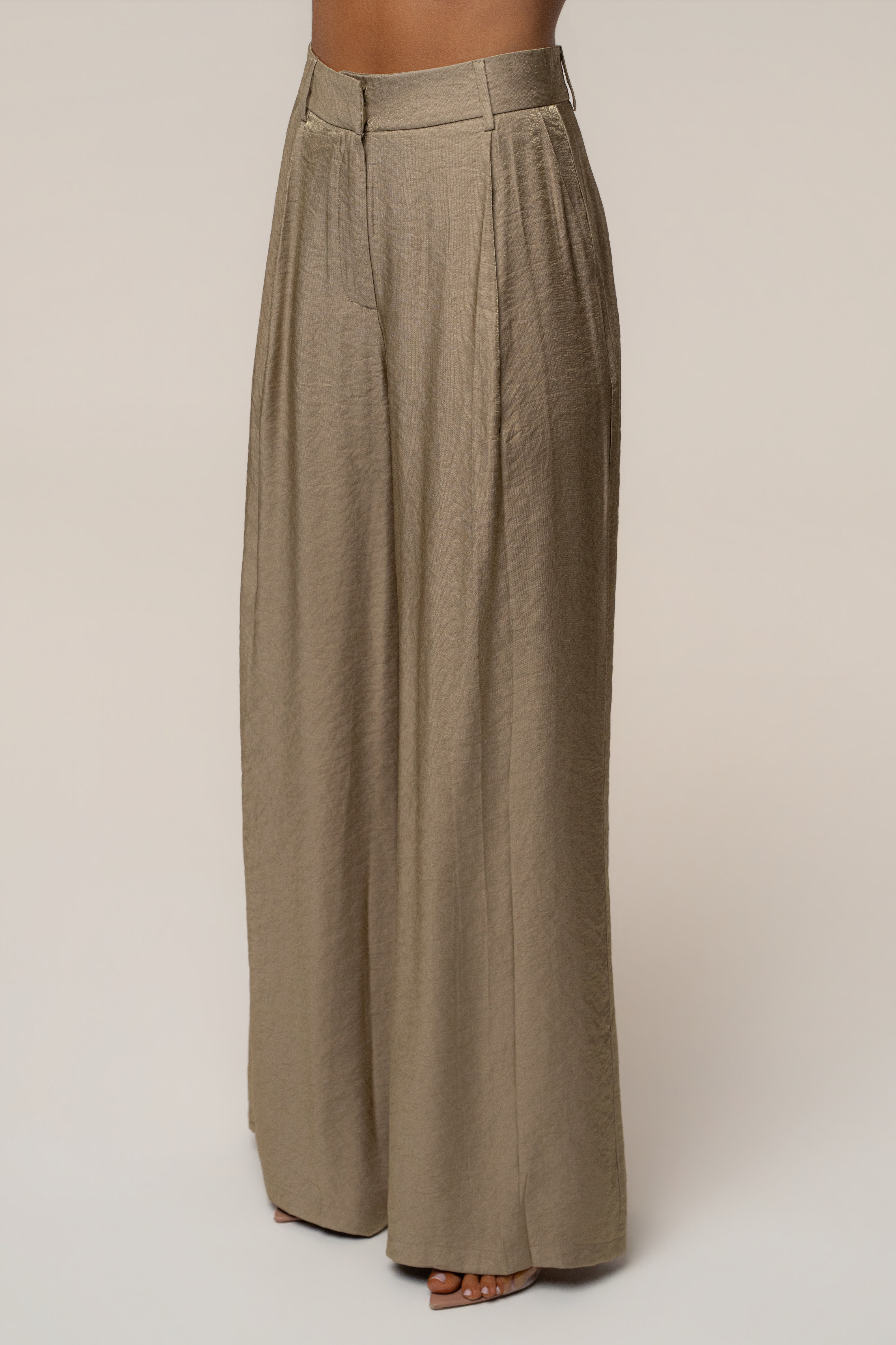 Back view of the outfit showing a white off the shoulder top and high waisted olive wide leg pants.