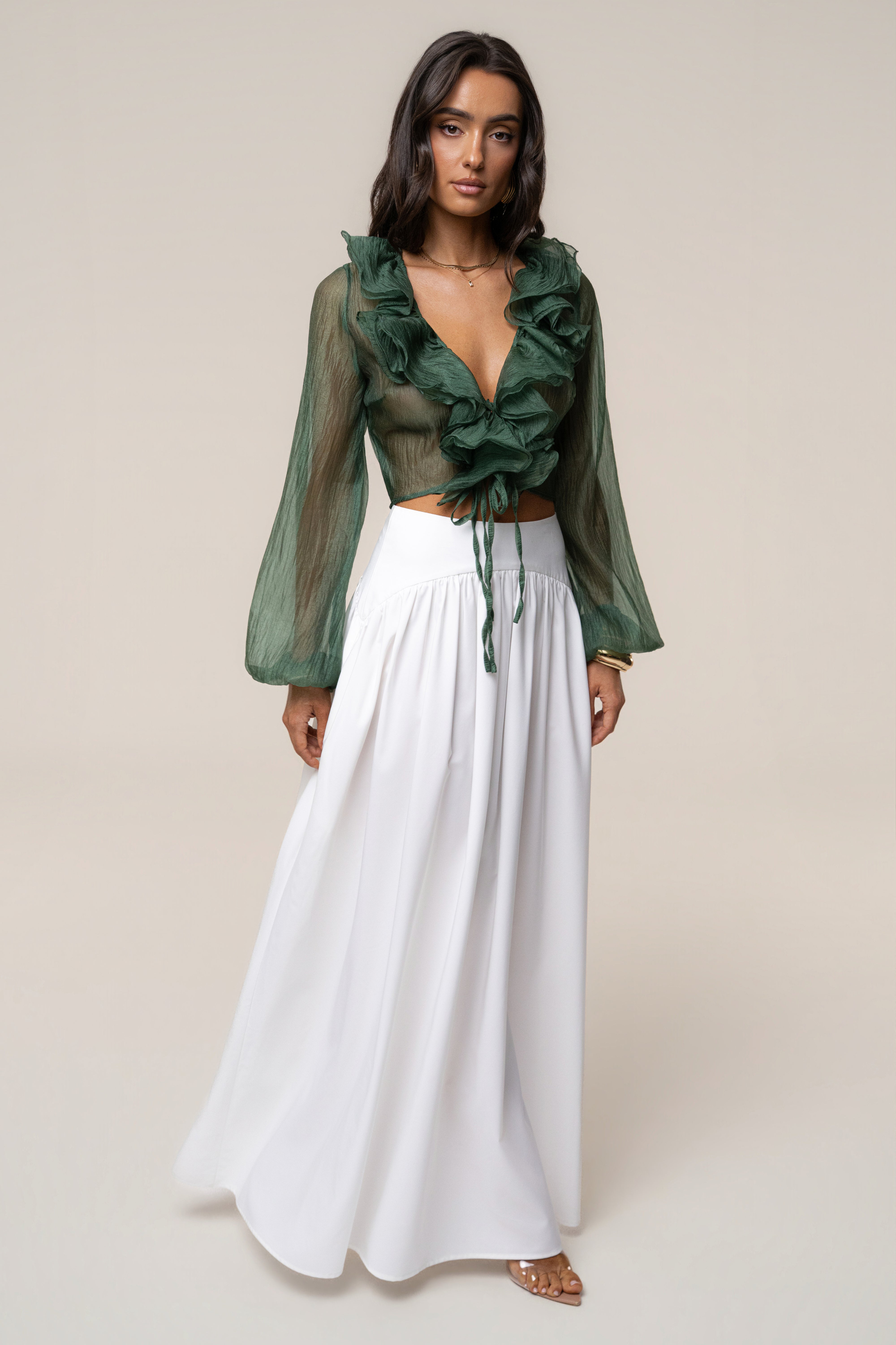 Model wearing green sheer Delilah top with cascading ruffles and white skirt