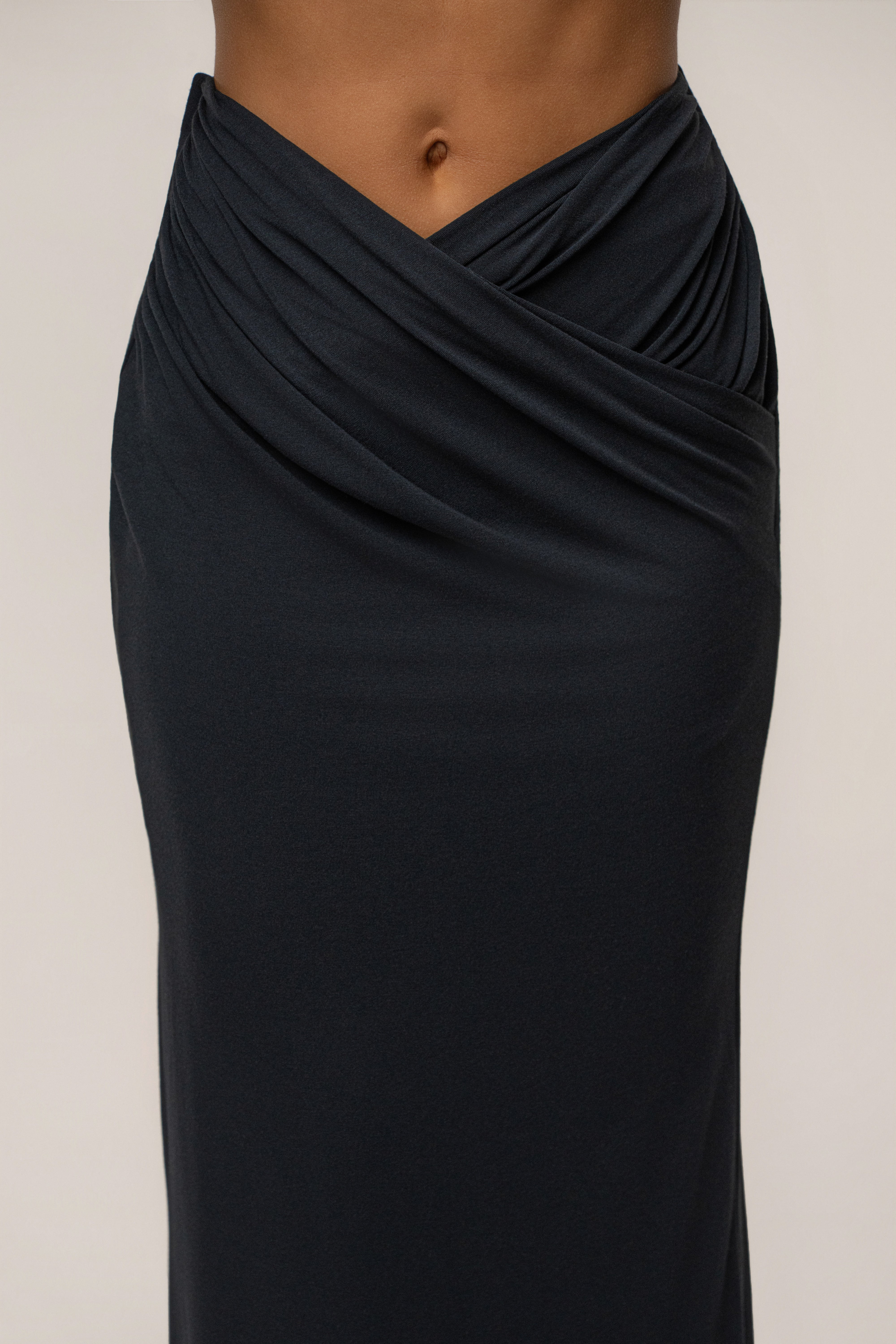 Close-up of the black maxi skirt waist showing a wrapped, draped front detail.