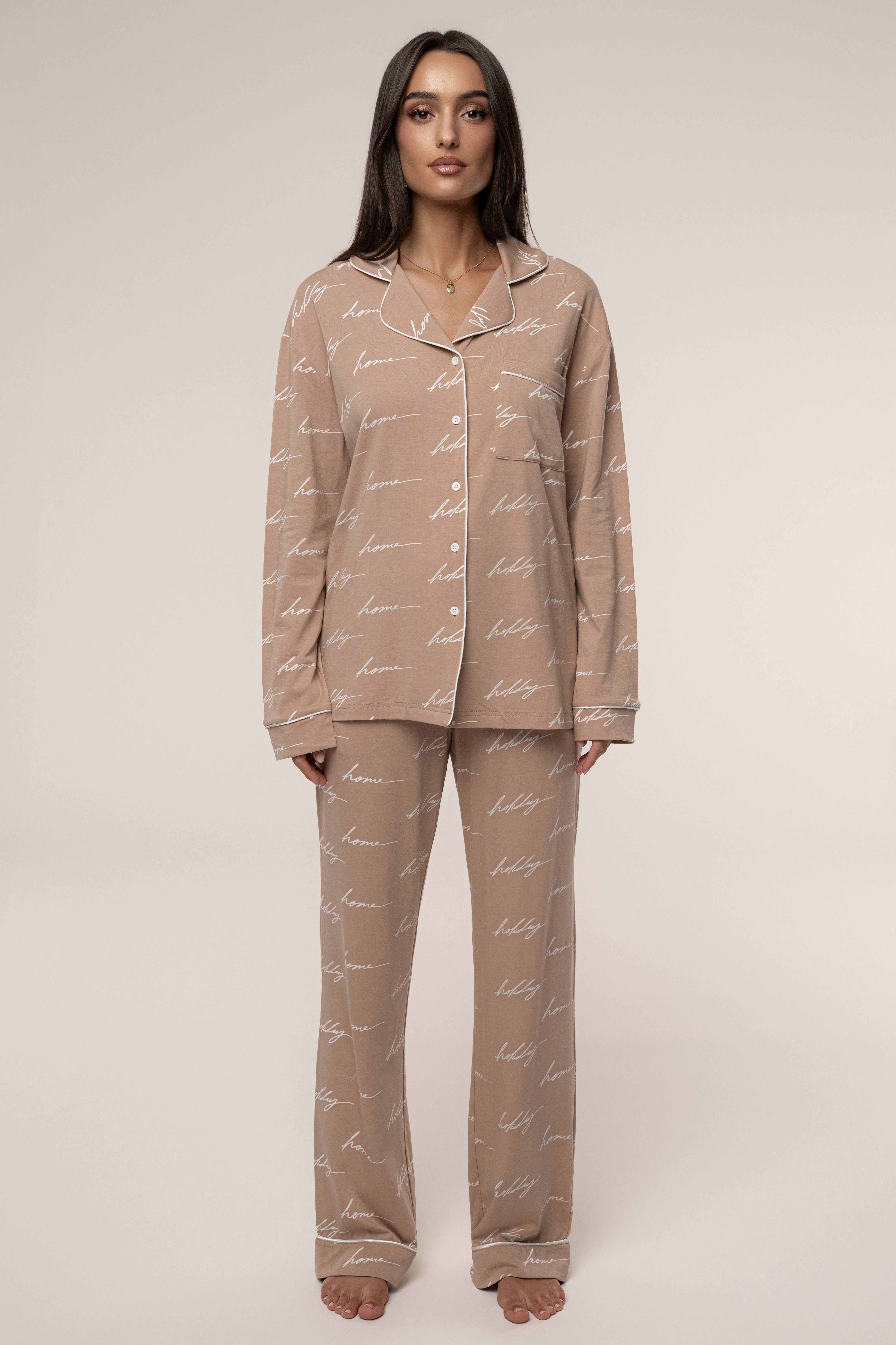 Woman wearing a beige pajama set with a subtle pattern on a plain background