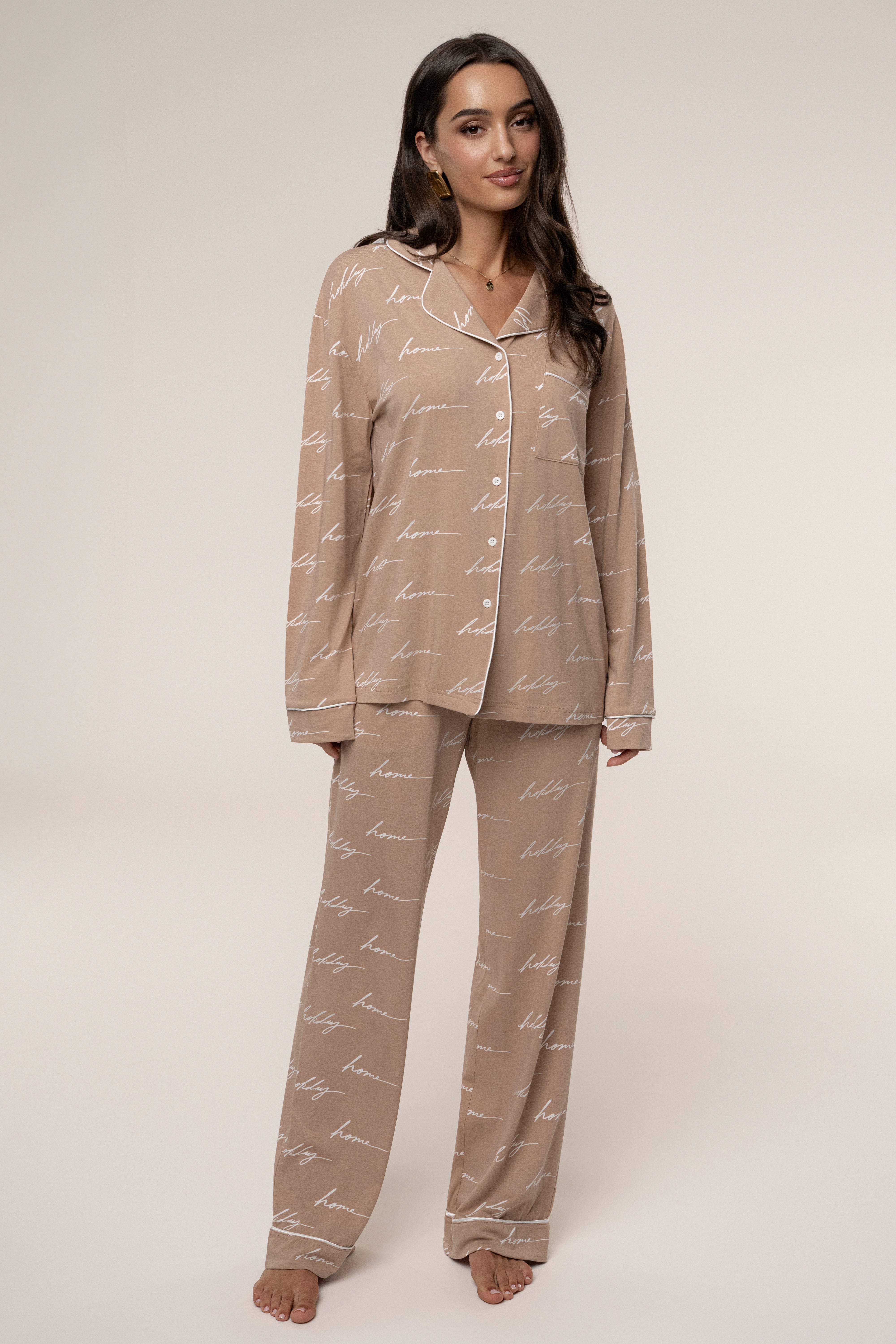Woman wearing a beige pajama set with a subtle pattern on a plain background