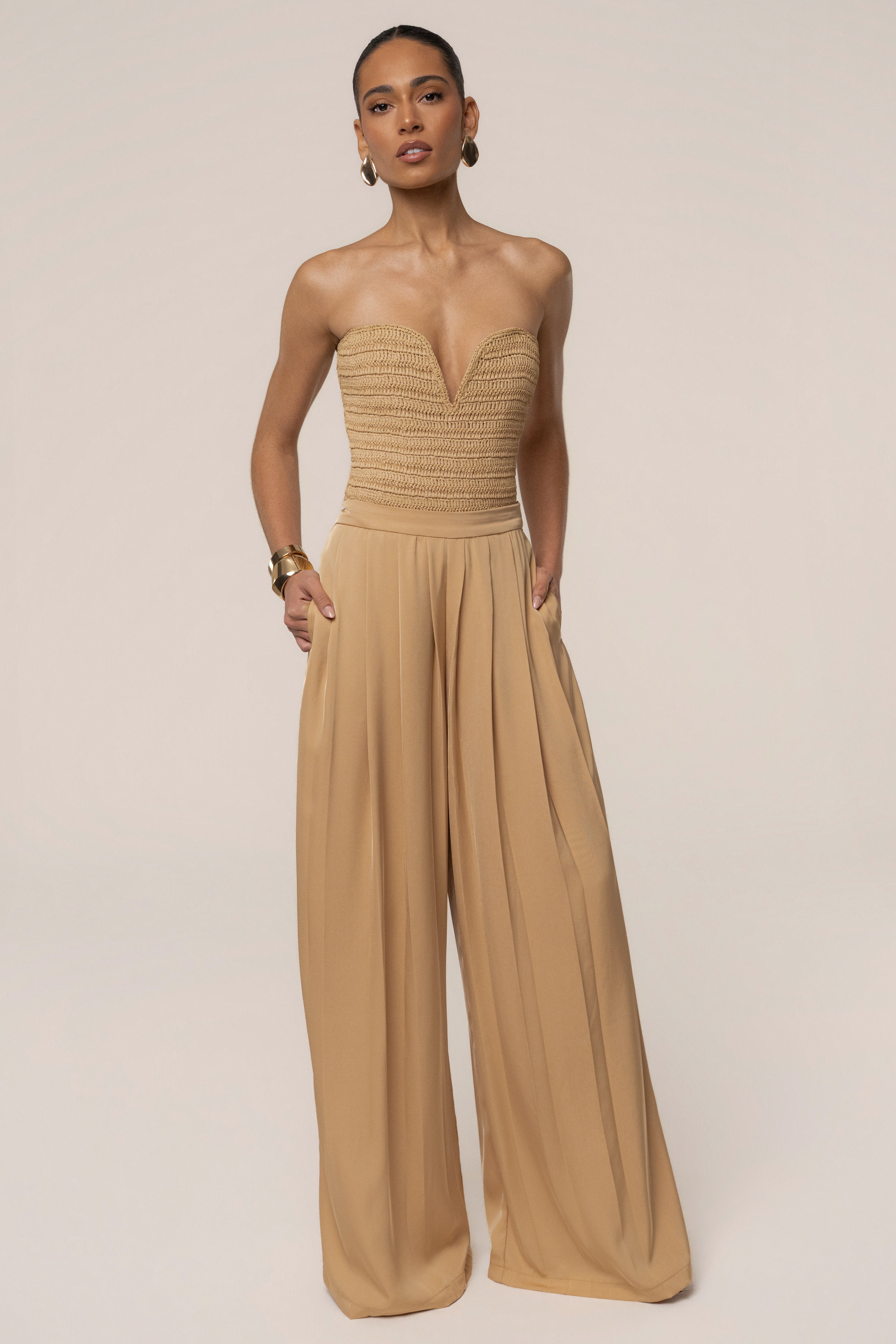 Beige Clara wide-leg pleated trousers by JLUXLABEL, stylish bottoms with a relaxed fit and elegant pleats, shown on a model.