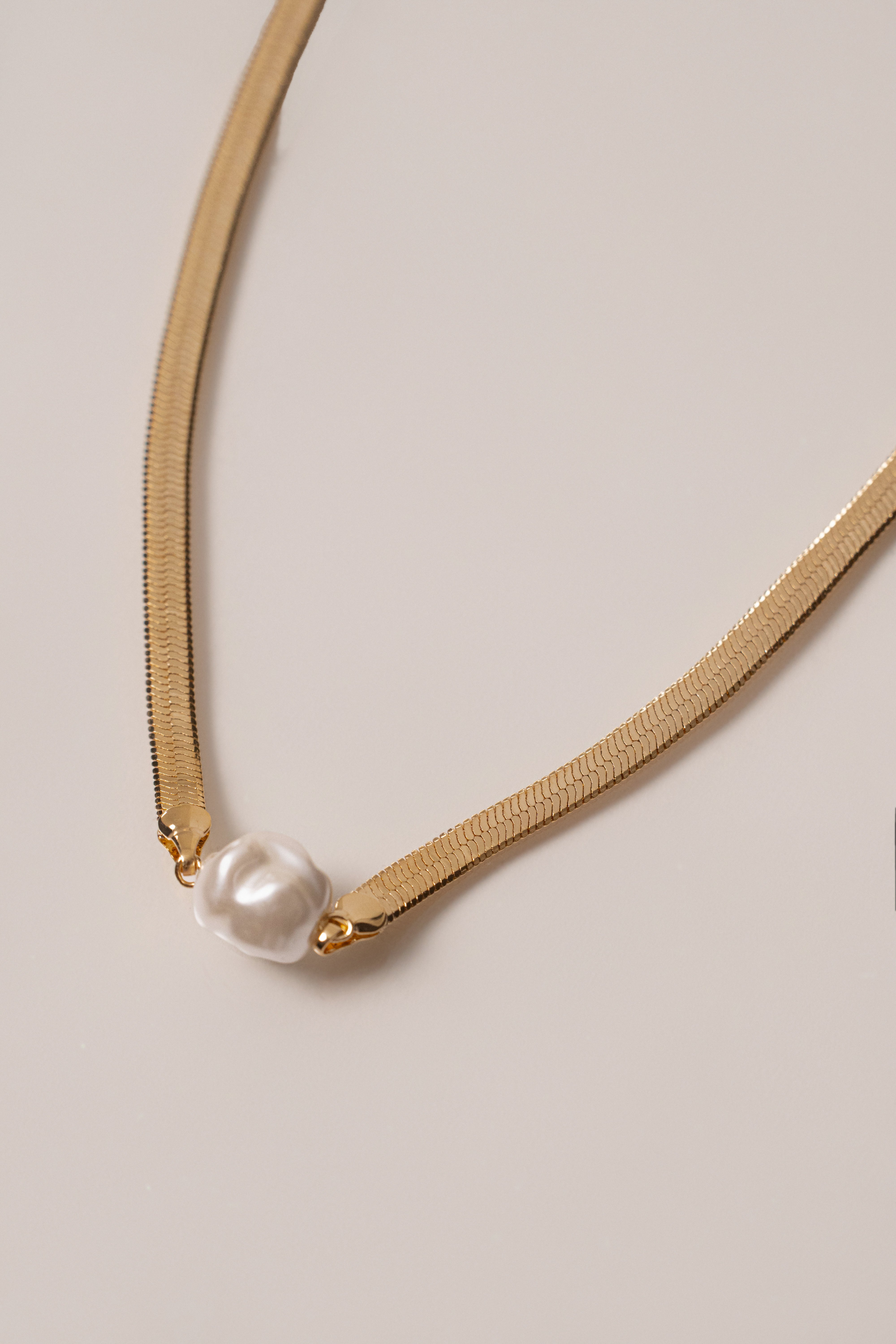 Gold pearl herringbone necklace from JLUXLABEL featuring a sleek, flexible jewelry design with lustrous pearls and gold chain.