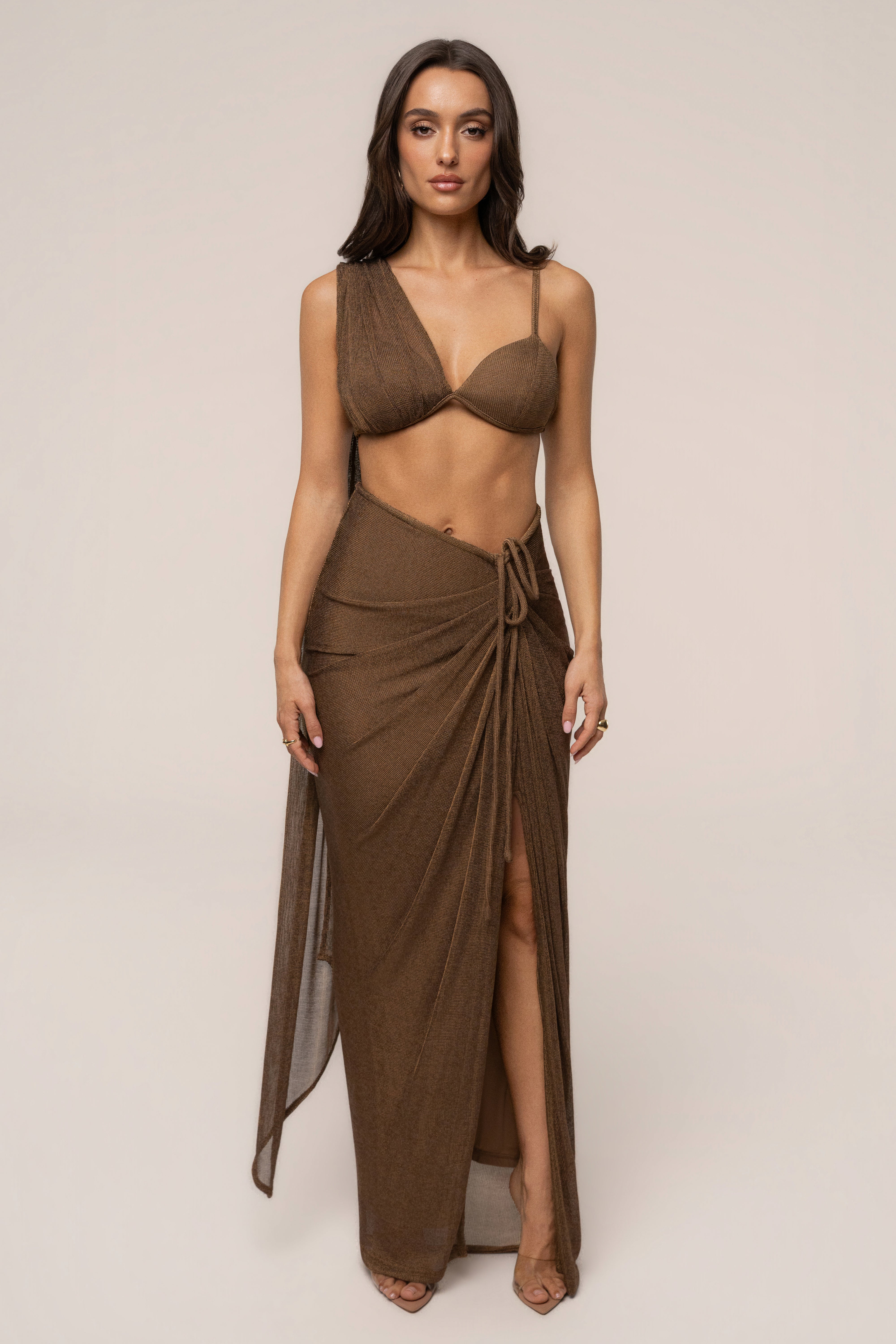 Bronze Noelia metallic slit skirt by JLUXLABEL, showing a shiny fabric with a high slit, styled as a fashionable bottoms piece.