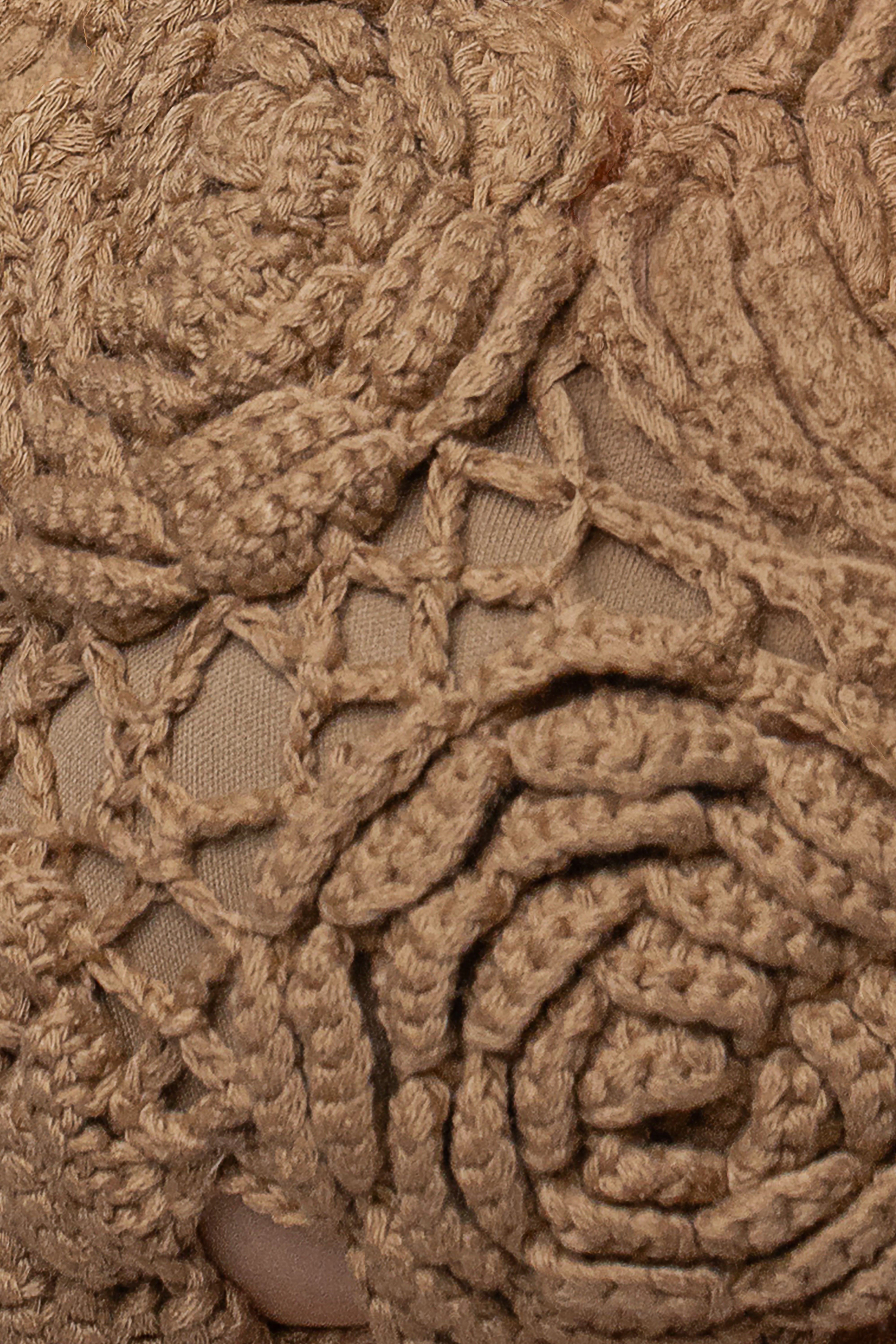 Close-up of khaki crochet bikini fabric with chunky yarn and ties.