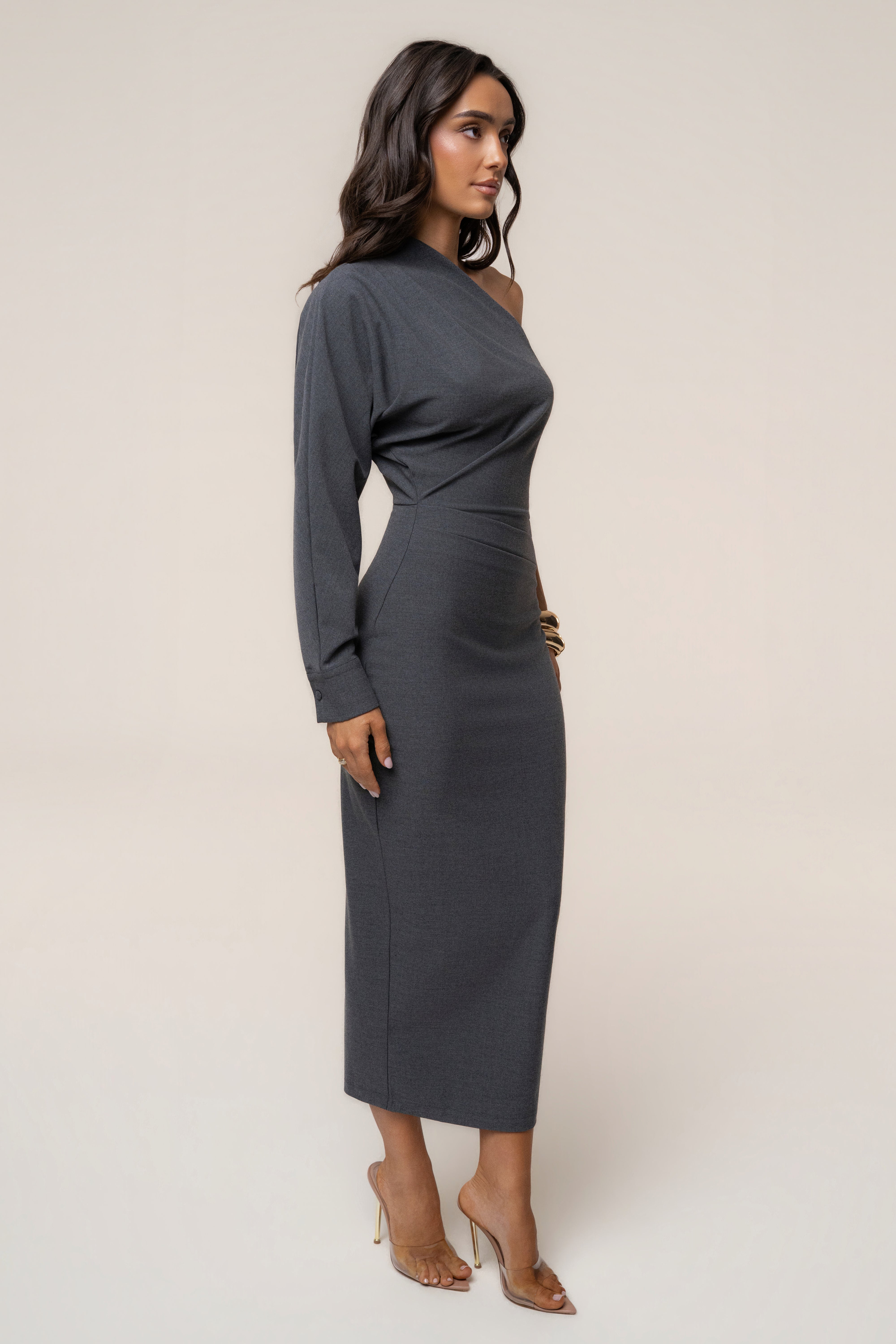 Side view of a woman in a grey one-shoulder Racheal midi dress