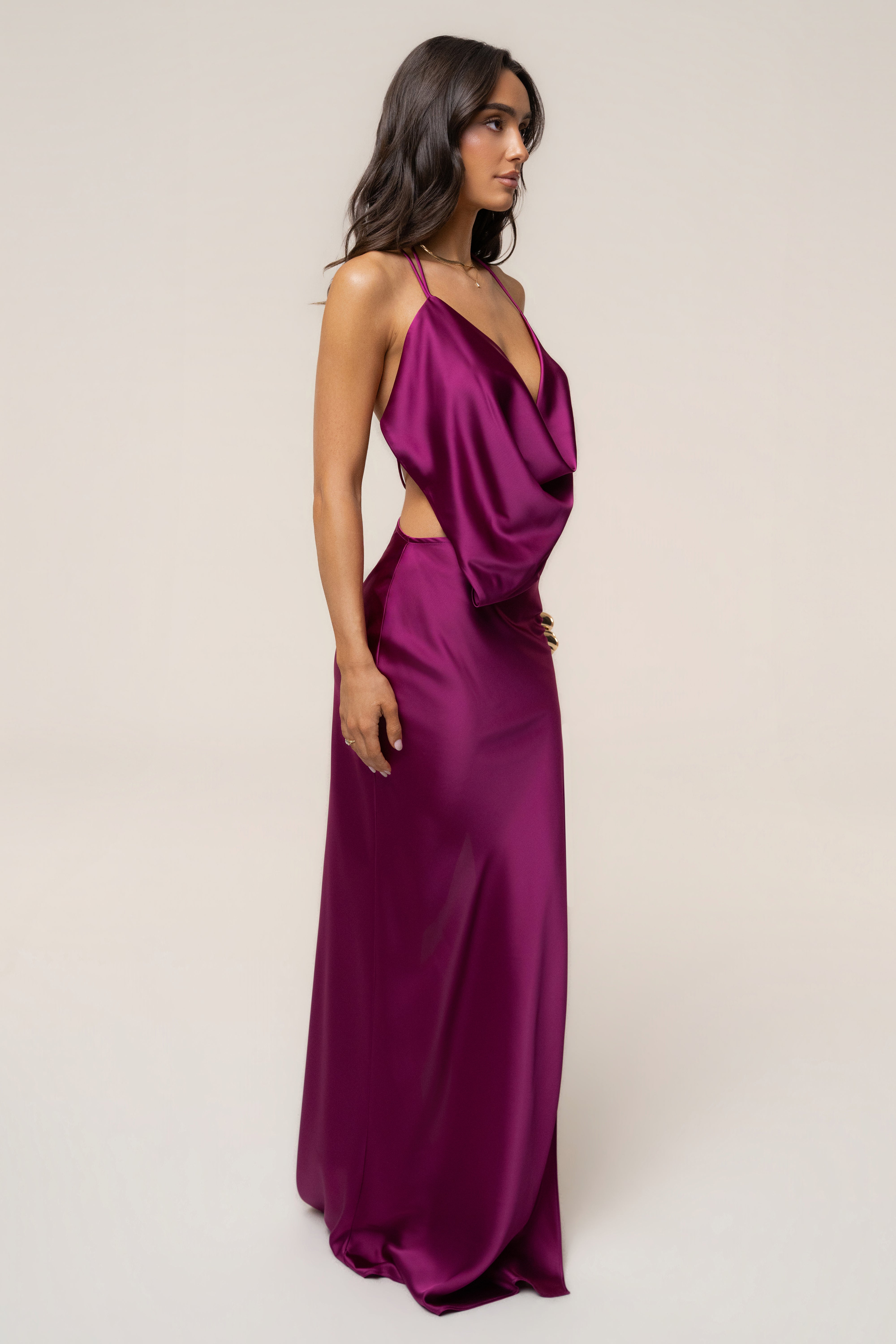 Side view of a model in a fuchsia Delmara Cowl Maxi Dress with a draped bodice two slim straps and waist cutout
