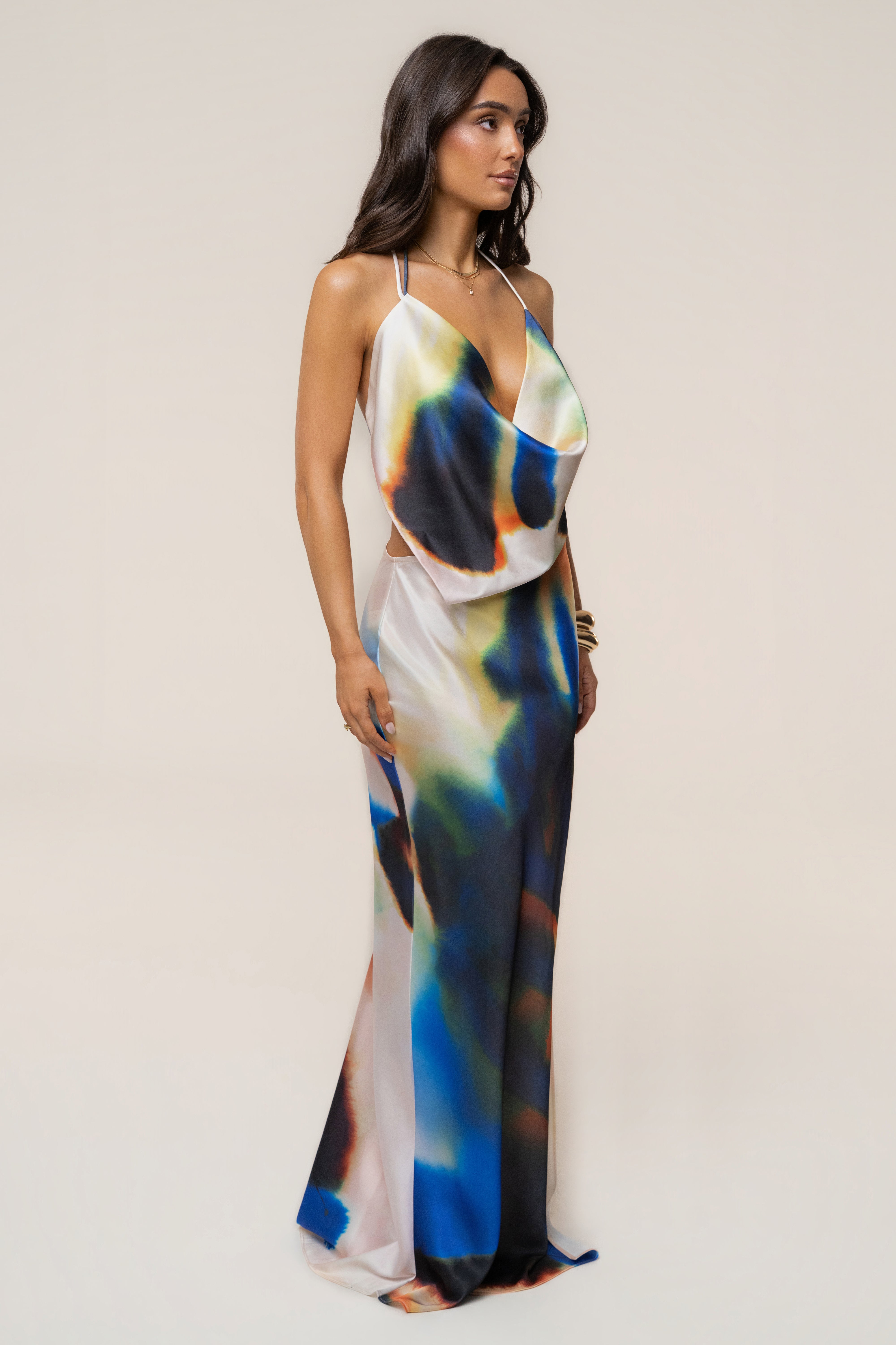 Front view of a model in a colorful tie-dye cowl maxi dress with thin white straps and a deep plunging neckline.