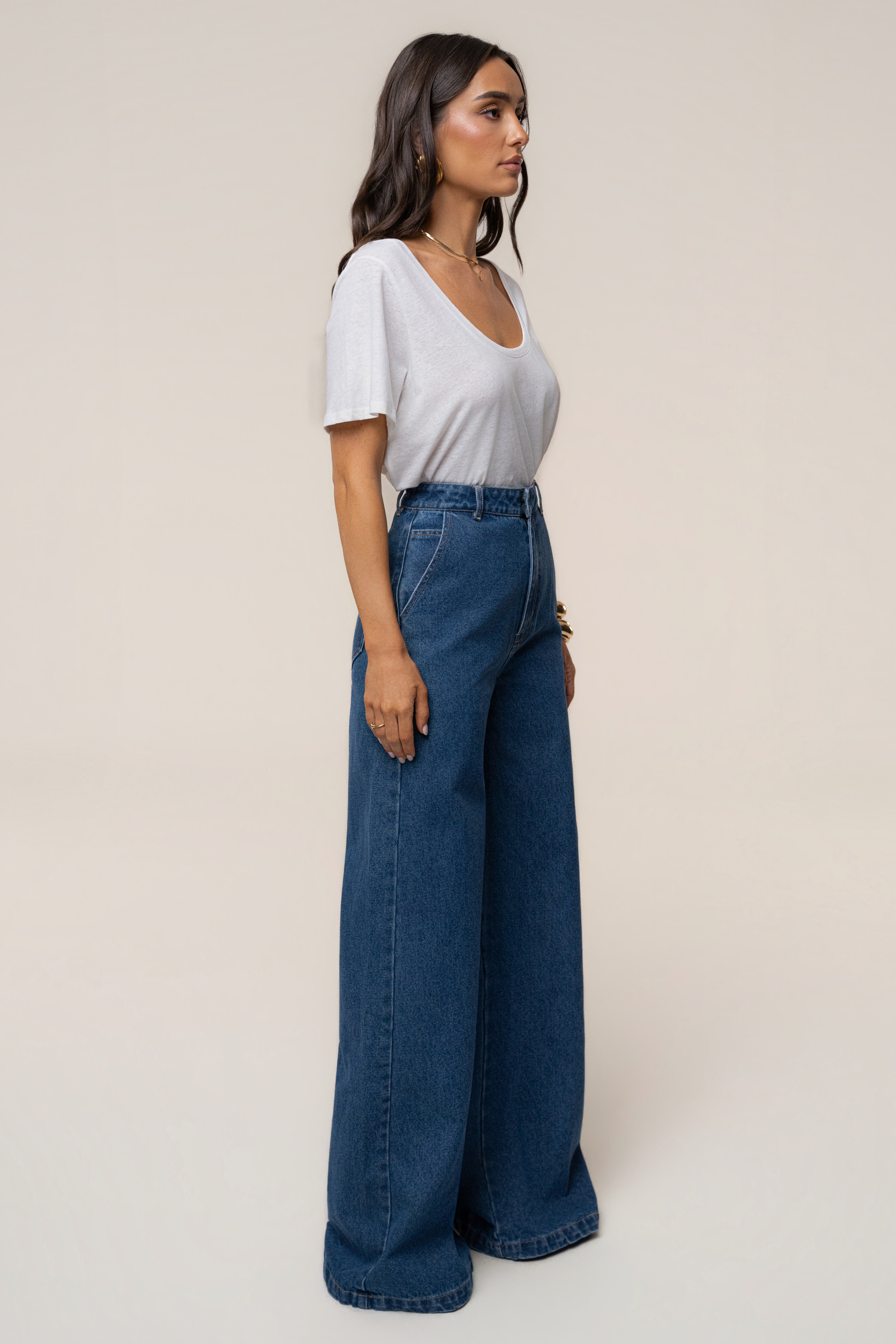 Side profile of a model in a white top tucked into high-waisted medium wash wide-leg jeans