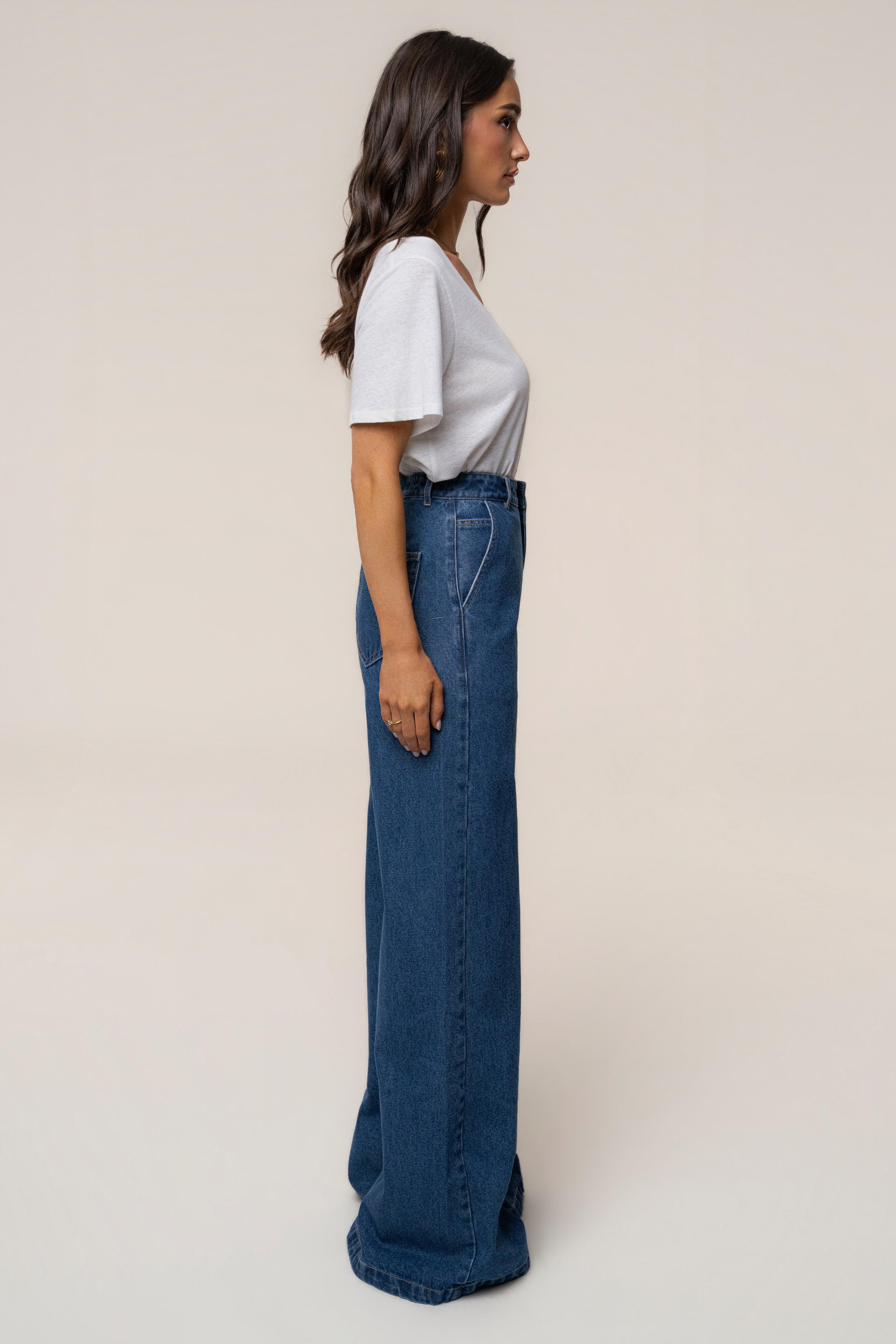 Profile of a model in a white tee tucked into high waist medium wash wide leg jeans.