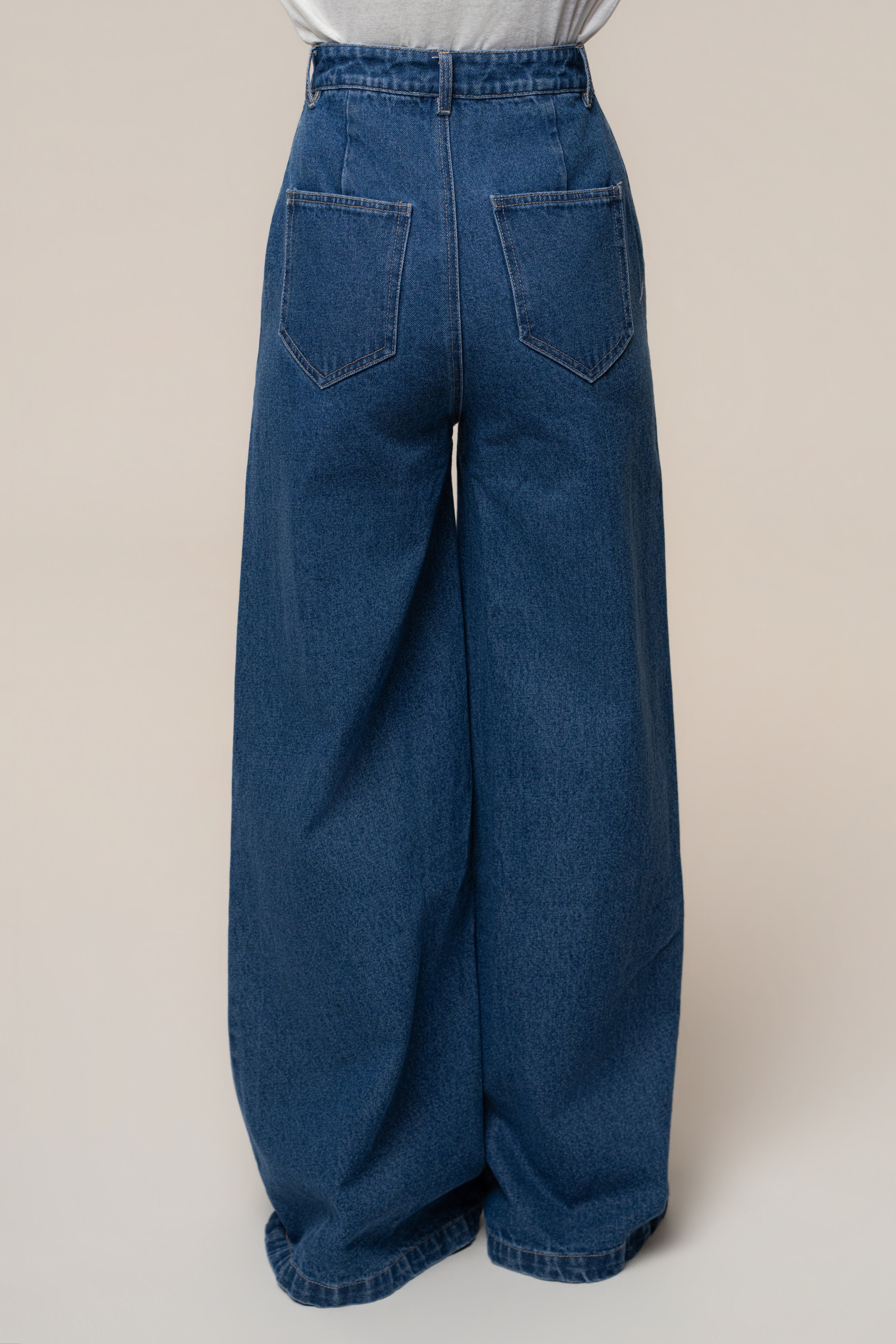 Back view of medium wash wide leg denim jeans highlighting high waist and back pockets.