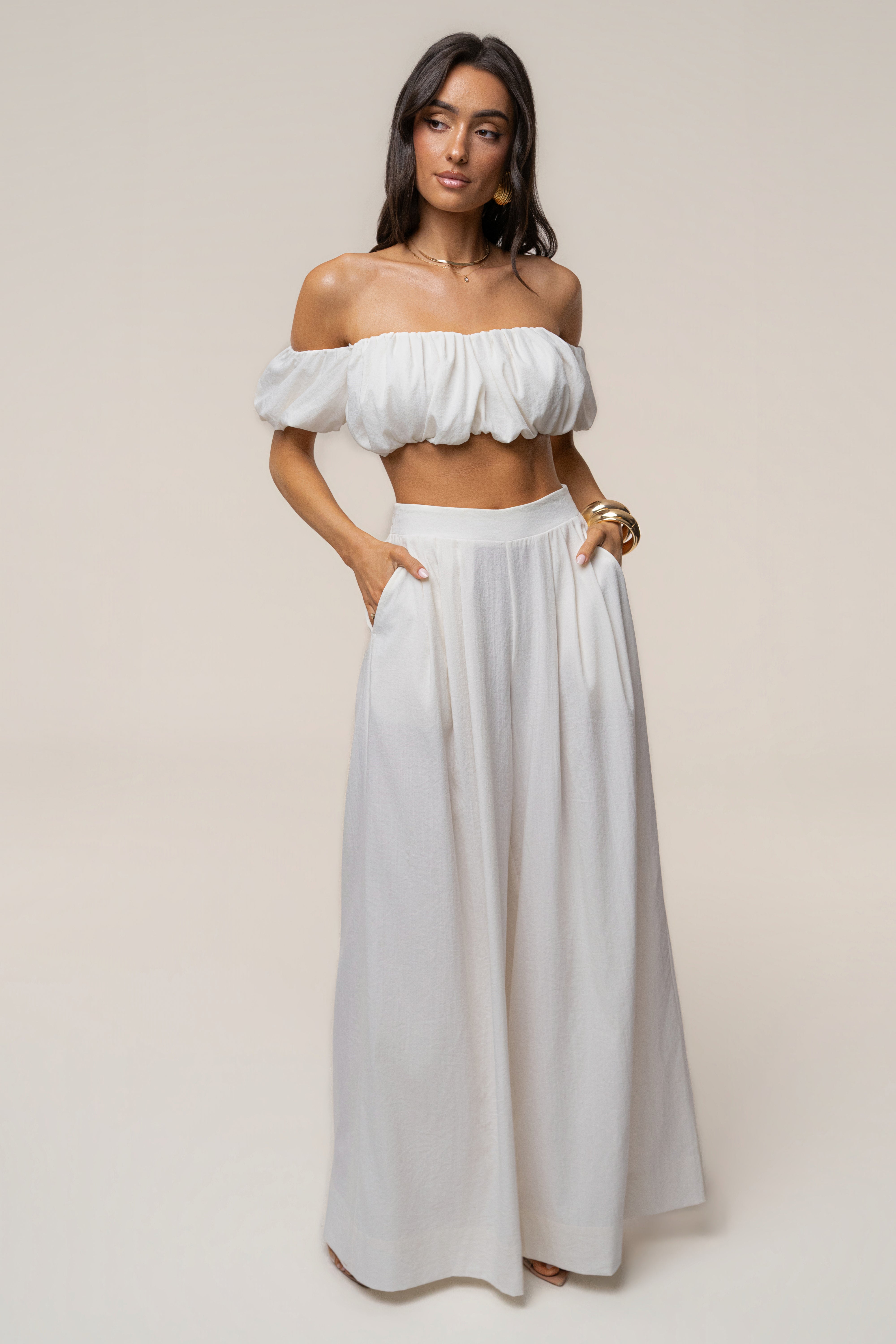 Model wearing ivory Sunset Breeze off the shoulder crop top with wide-leg pants