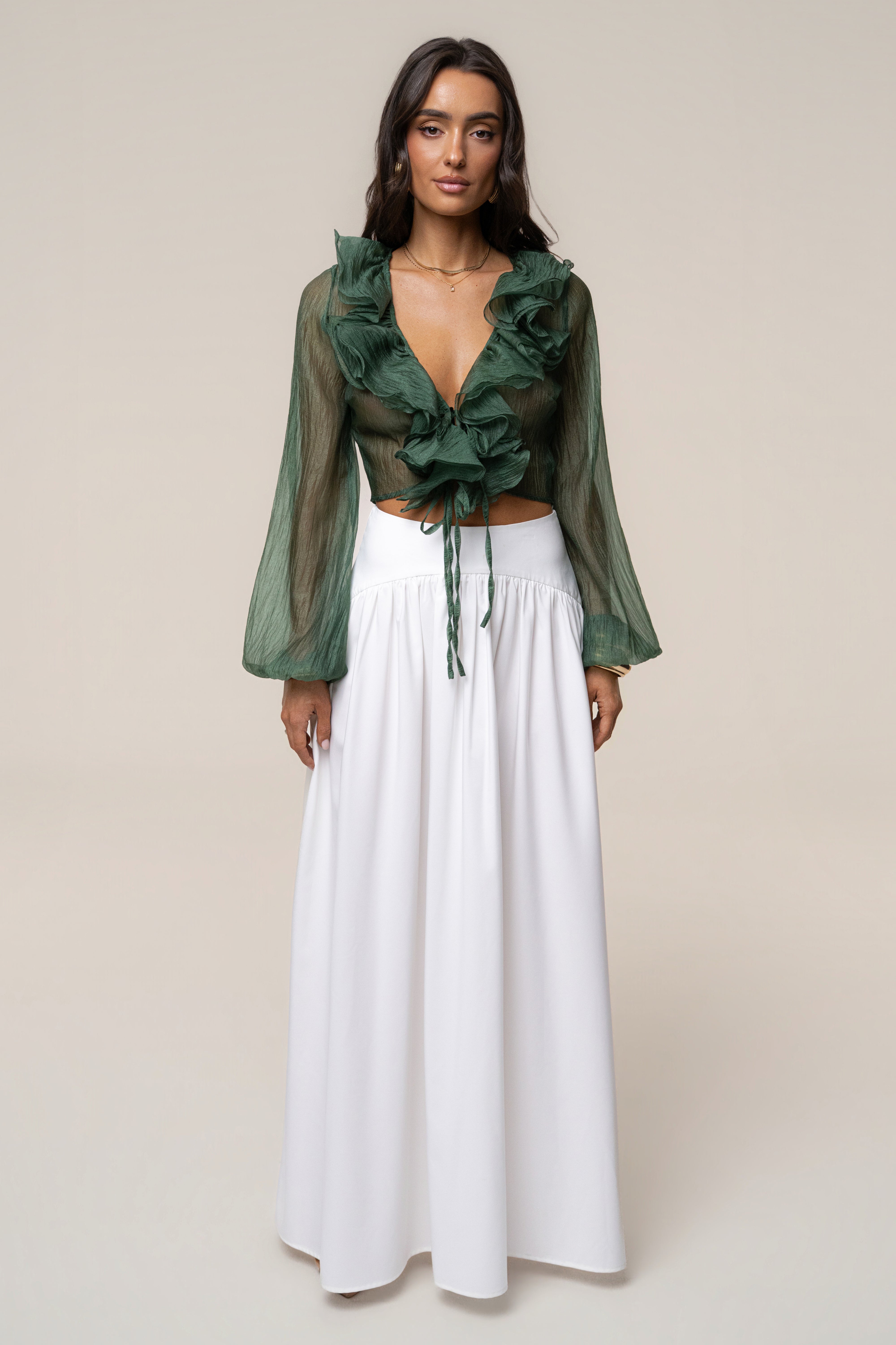Close up of the green Delilah top showing sheer fabric and layered ruffles at the neckline with gold jewelry.