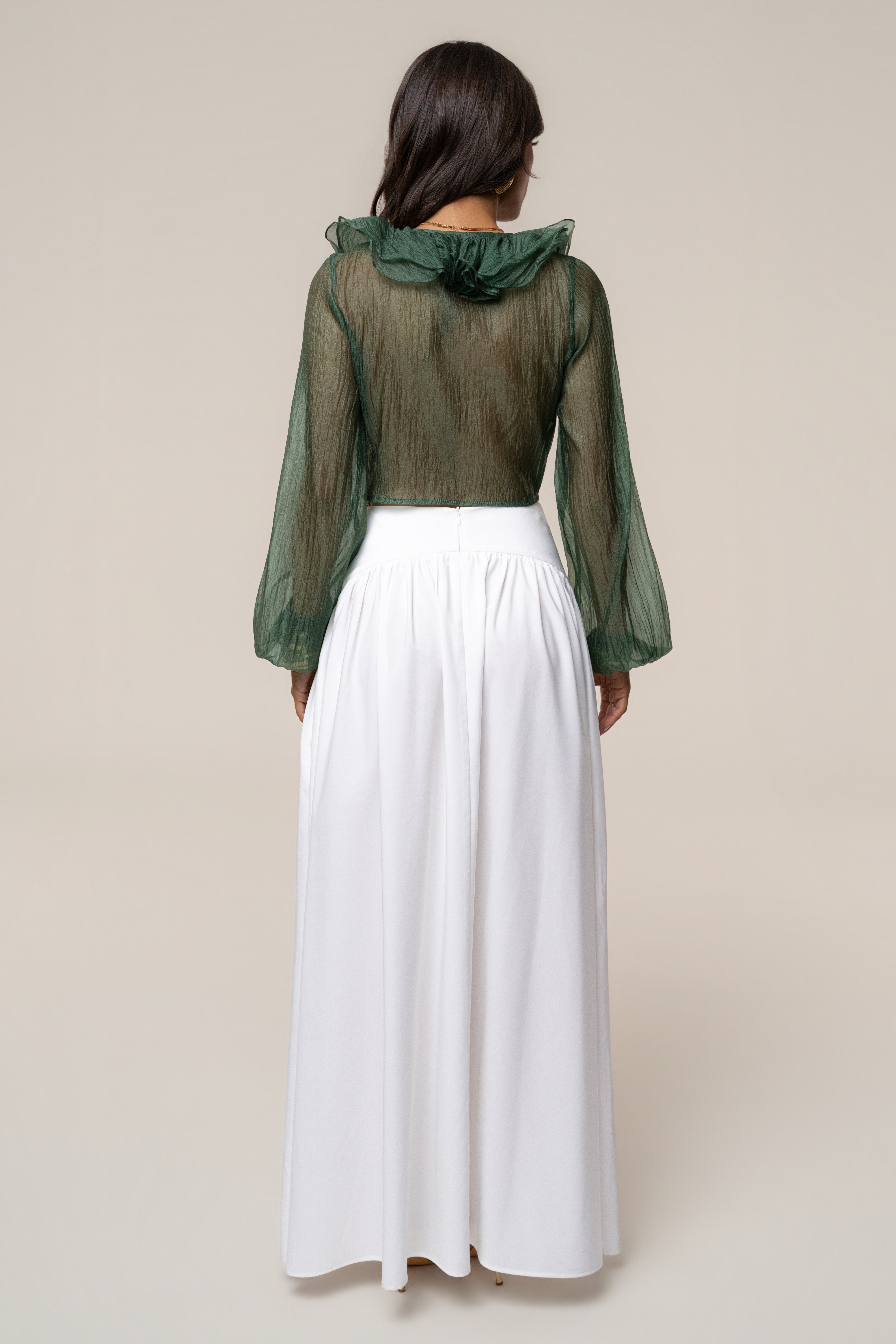 Back view of a woman in a sheer green Delilah Ruffled Top with a large ruffle collar along the back