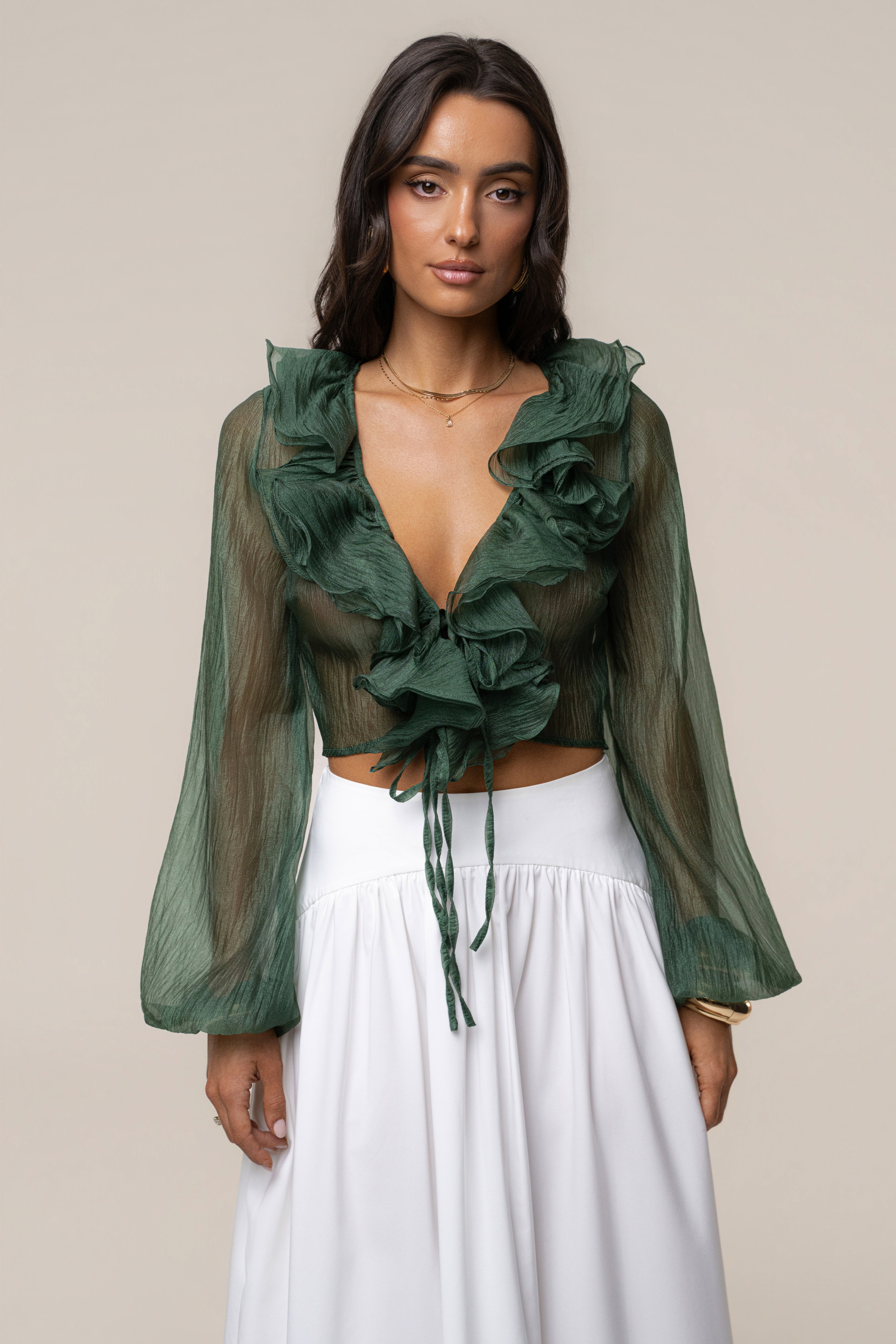 Model wearing a green sheer Delilah ruffled top with voluminous sleeves and waist tie.