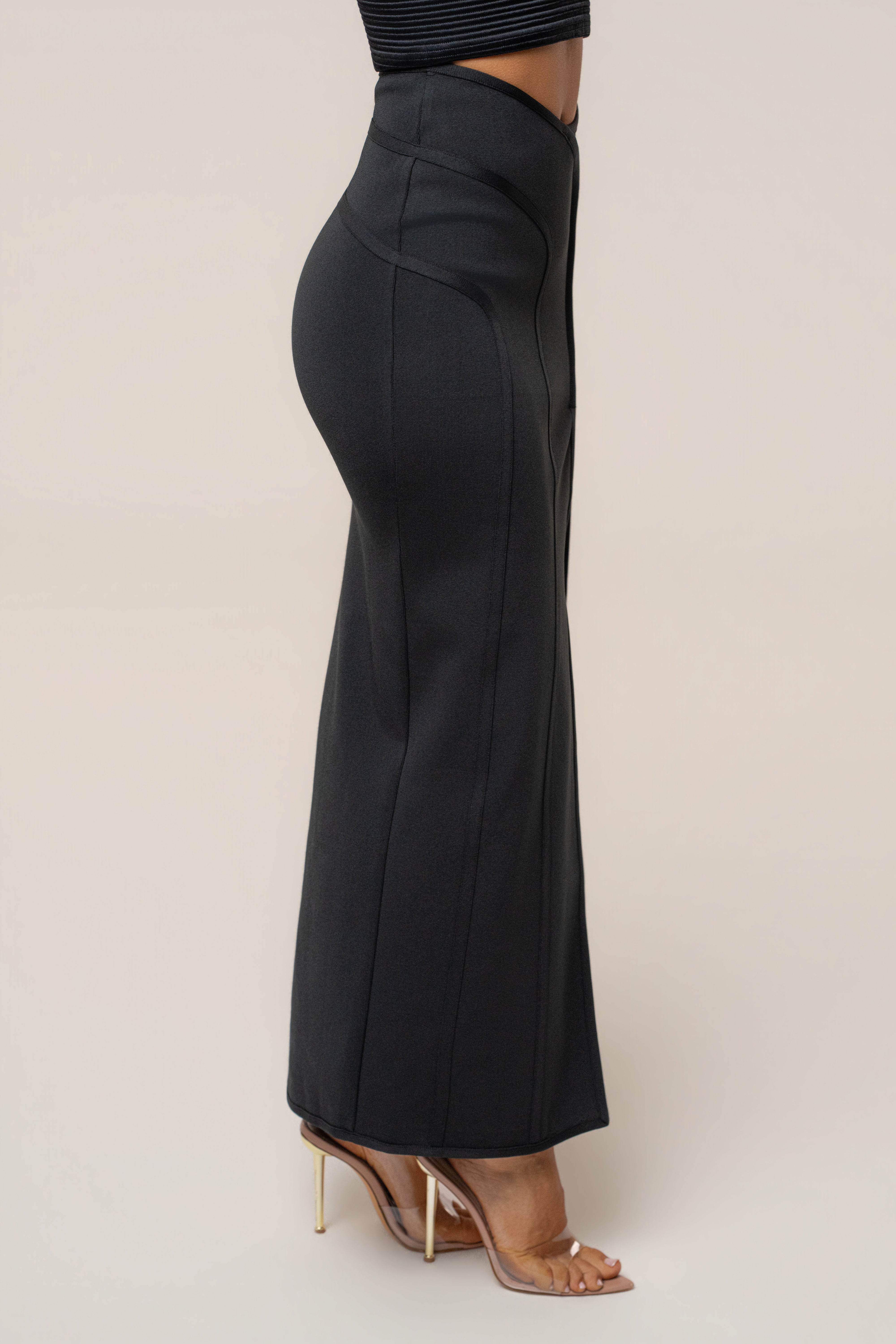 Side profile of the black maxi skirt fitting closely from waist to ankle.