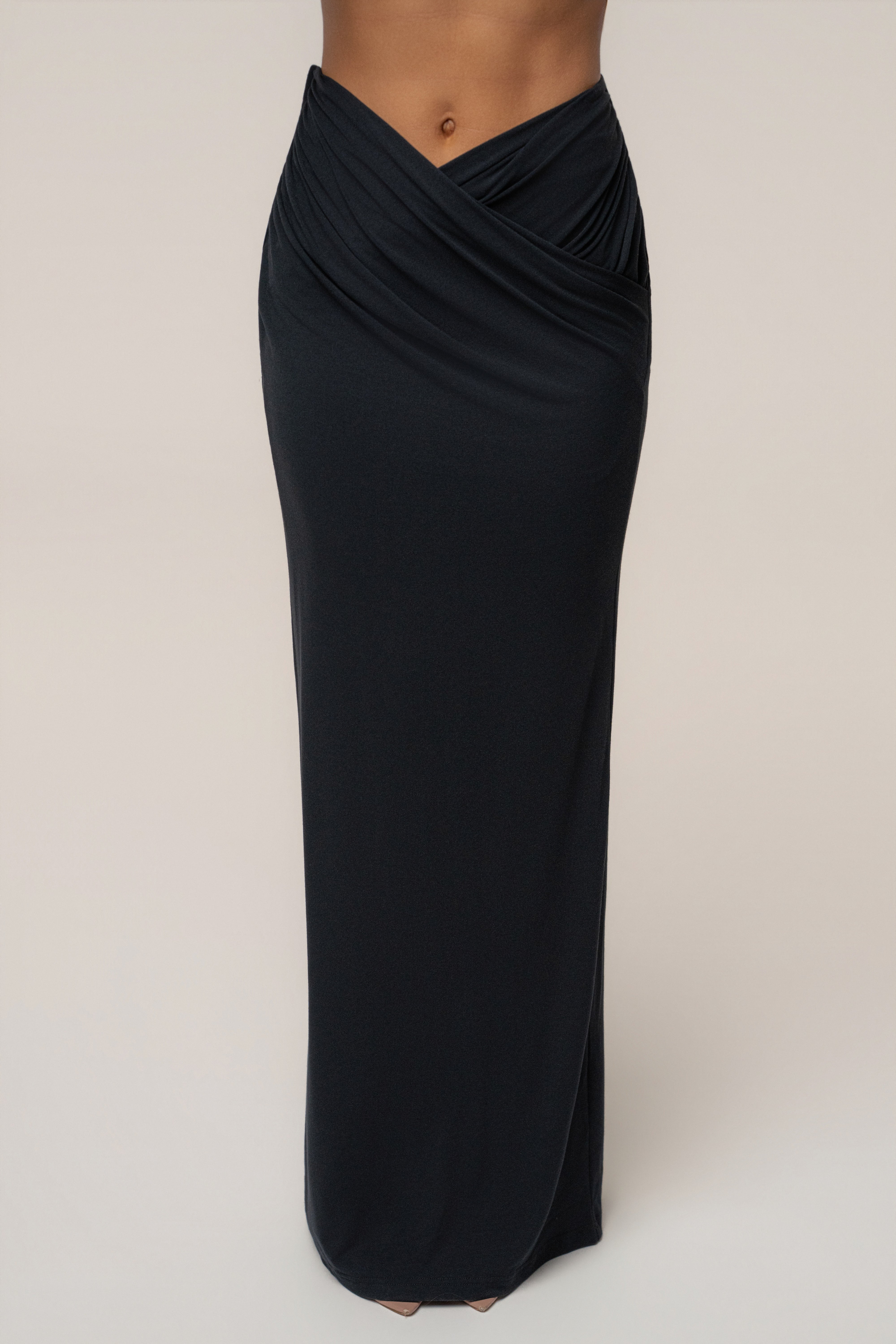 Front view of a black maxi skirt with a twisted draped waist detail