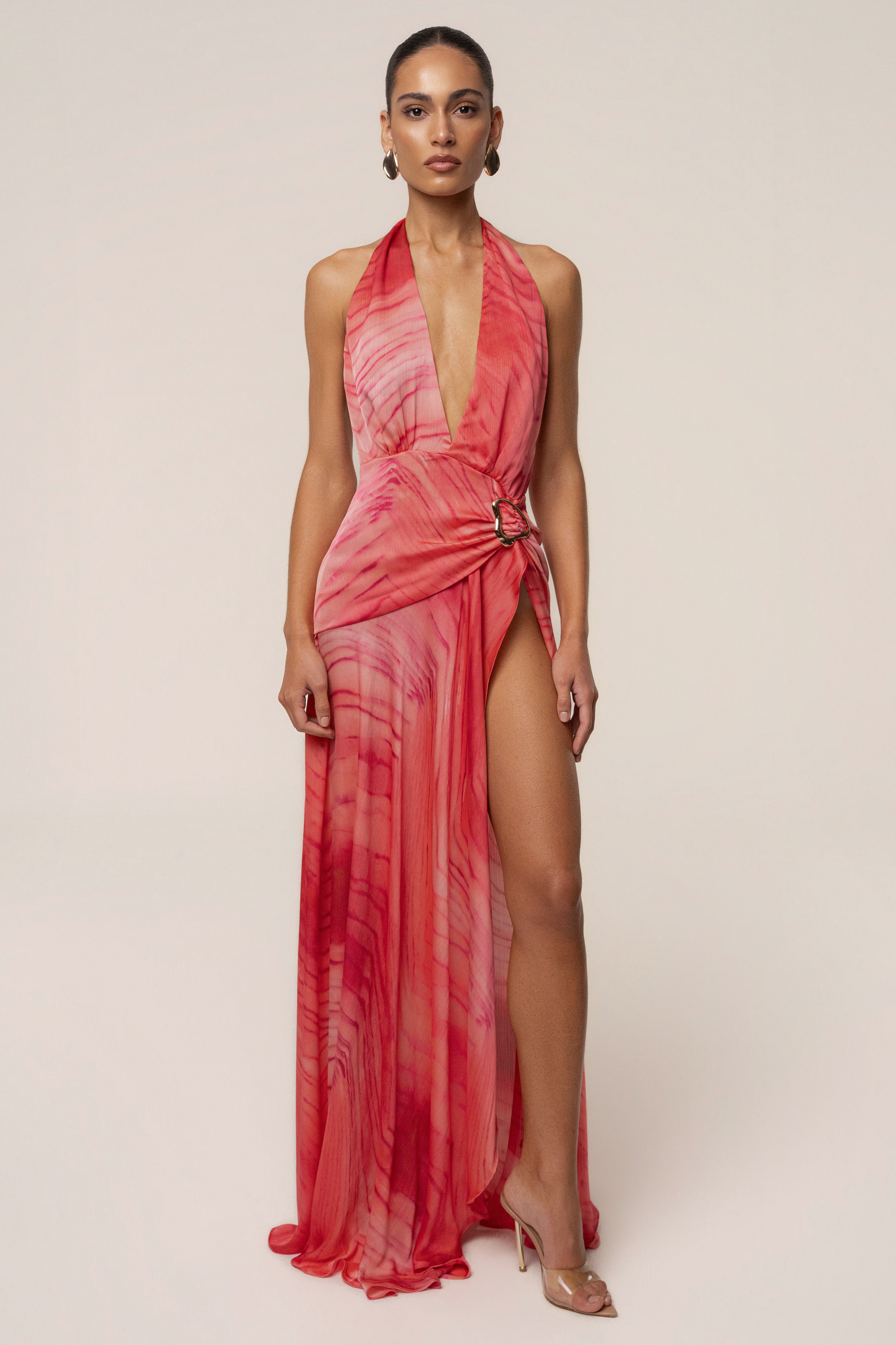 Model wearing coral red halter neck maxi dress with wrap detail and side buckle.