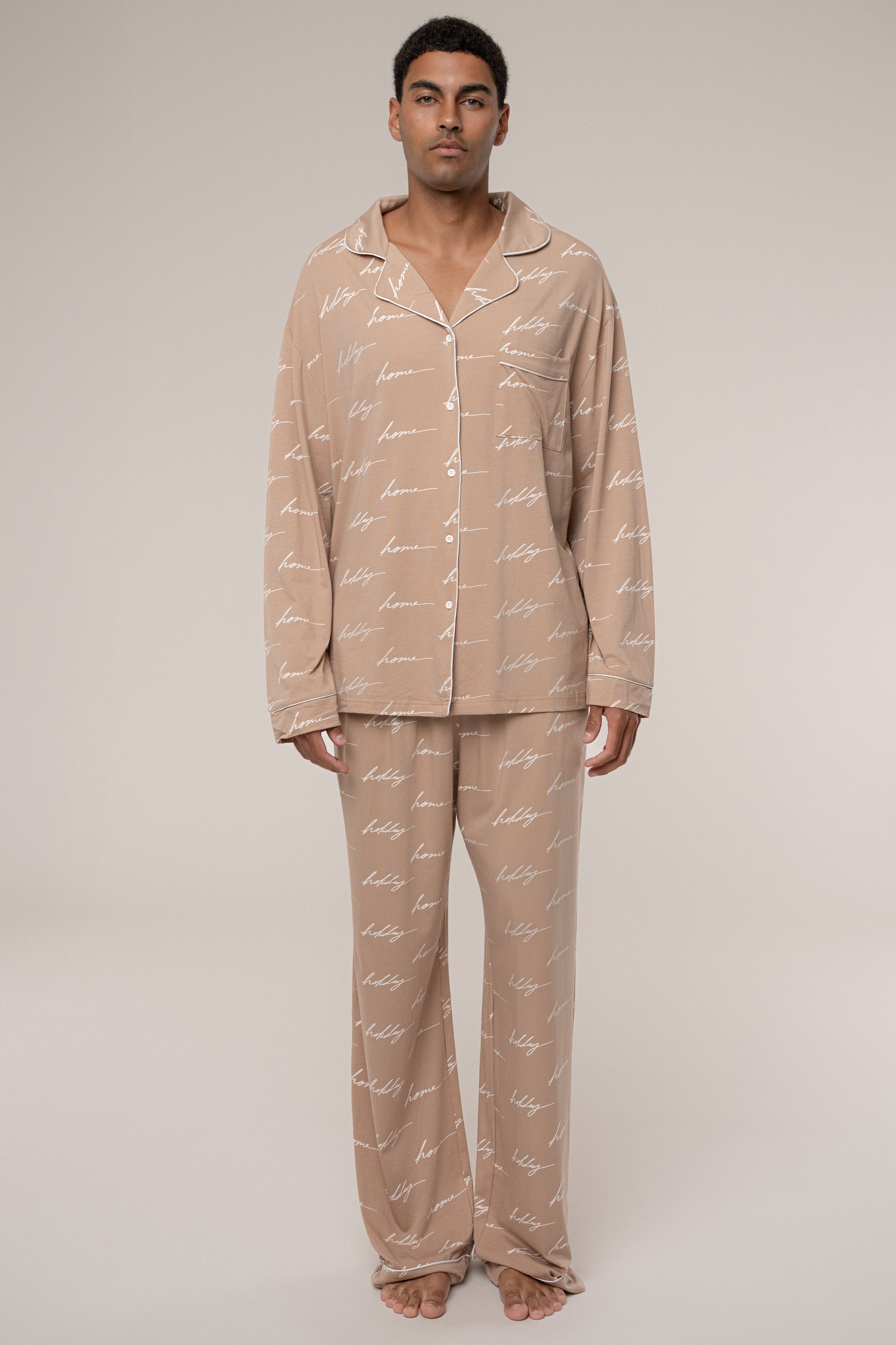Man wearing beige pajama set with text pattern on a plain background